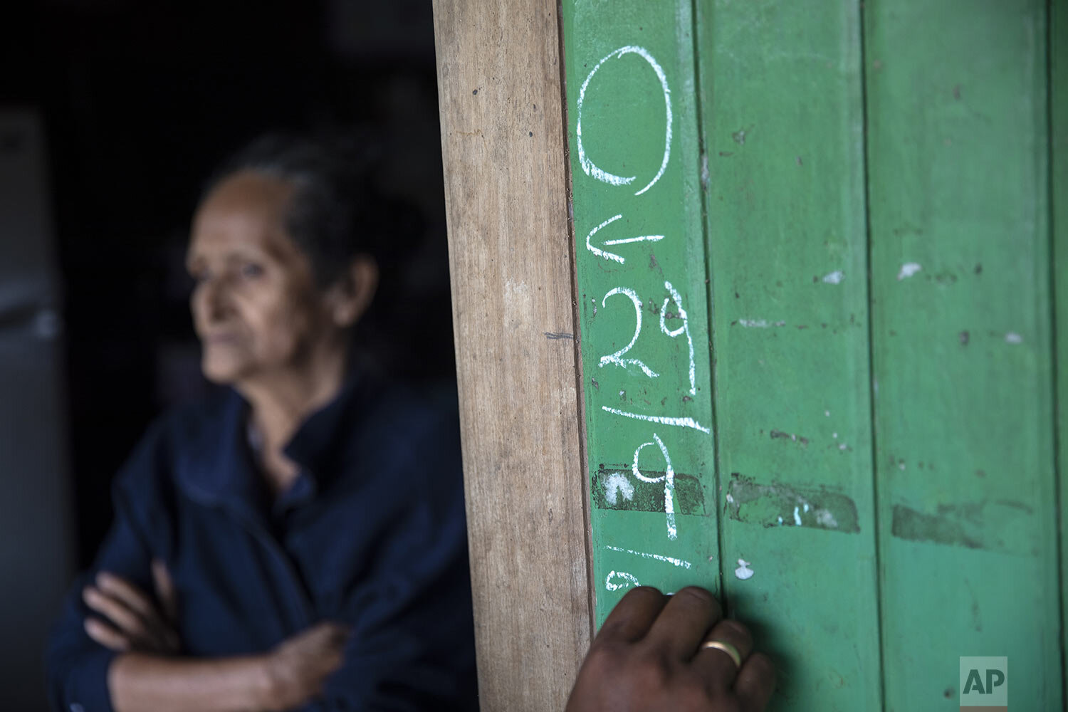  Leila Ramirez, who is suffering from dengue, stands in her doorway as a member of the campaign against dengue documents their visit on the wood siding of her home, in Pucallpa, n PeruÕs Ucayali region, Tuesday, Sept. 29, 2020. Five members in Ramire