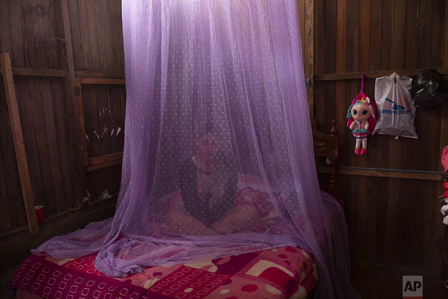  Valentina Esperanza, who is recovering from dengue, sits on her bed protected by mosquito netting as she watches a television program at her home in Pucallpa, in Peru’s Ucayali region, Tuesday, Sept. 29, 2020. (AP Photo/Rodrigo Abd) 