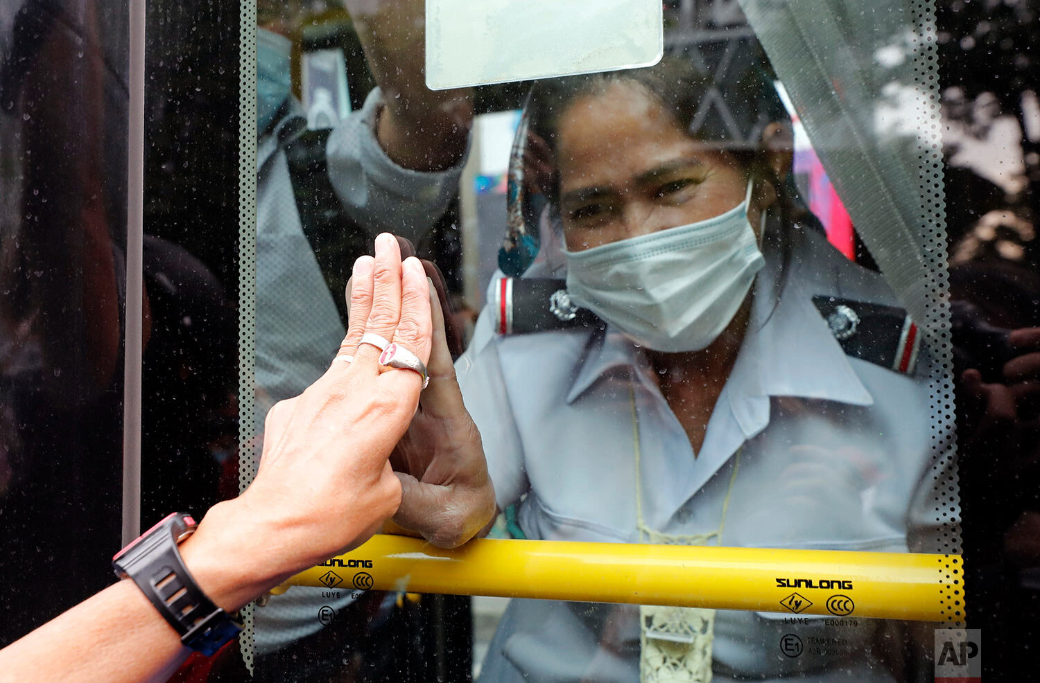  A pro-democracy protester, partly seen at left, and a bus ticket clerk, right,  three-finger flash each other, in Bangkok, Thailand, Sunday, Oct. 25, 2020. (AP Photo/Sakchai Lalit) 