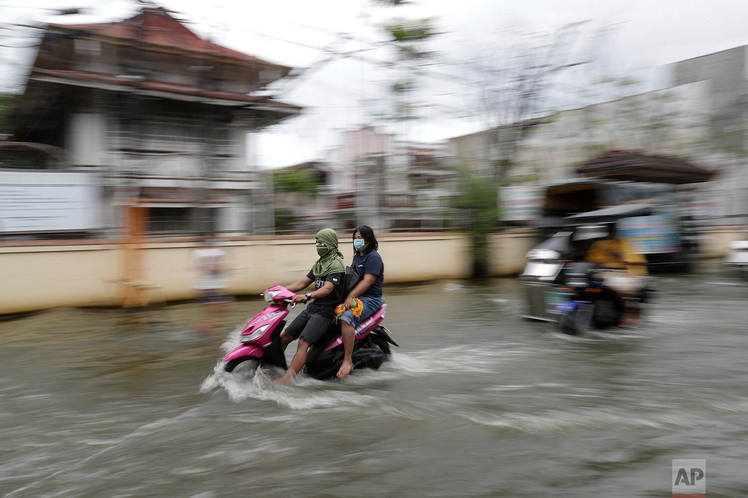  Residents wearing masks to prevent the spread of the coronavirus ride motorcycles as they negotiate a flooded road due to Typhoon Molave in Pampanga province, northern Philippines on Monday, Oct. 26, 2020. (AP Photo/Aaron Favila) 