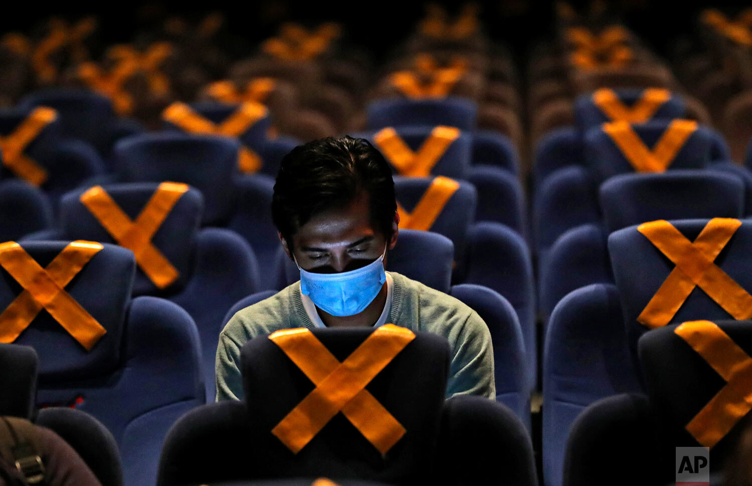  A man checks his mobile phone as he sits amid physical distancing markers prior to the start of a movie at CGV Cinemas theater in Jakarta, Indonesia, Friday, Oct. 23, 2020.  (AP Photo/Tatan Syuflana) 