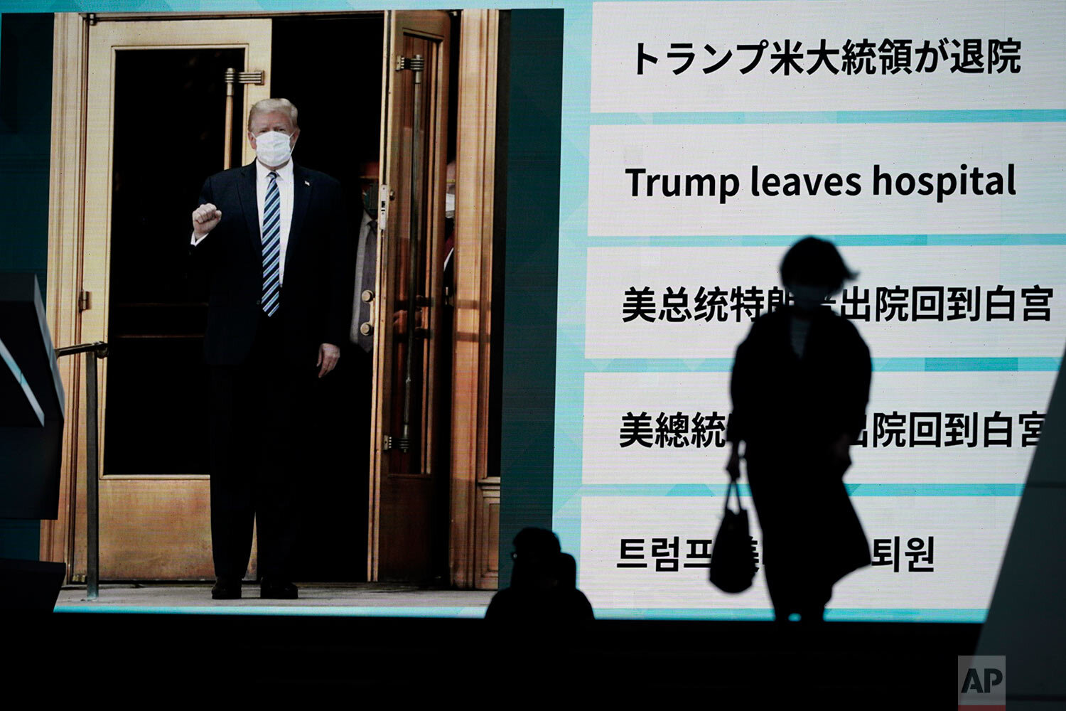  People walk past a screen showing the news report that President Donald Trump has left a hospital to return to the White House after receiving treatments for COVID-19, Tuesday, Oct. 6, 2020, in Tokyo. (AP Photo/Eugene Hoshiko) 