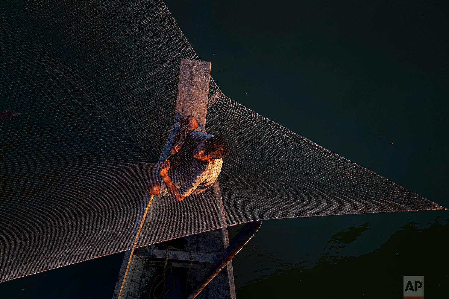  An Indian fisherman fixes his fishing net sitting on a country boat on the outskirts of Gauhati, India, Wednesday, Oct. 14, 2020. (AP Photo/Anupam Nath) 