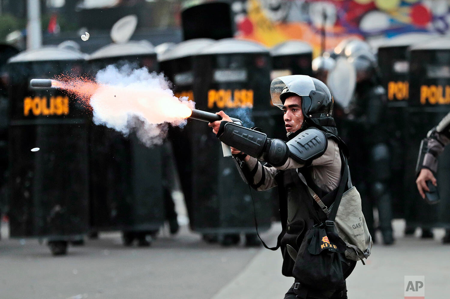  A police officer fires a projectile towards protesters during a rally against a controversial bill on job creation in Jakarta, Indonesia, Thursday, Oct. 8, 2020.  (AP Photo/Dita Alangkara) 