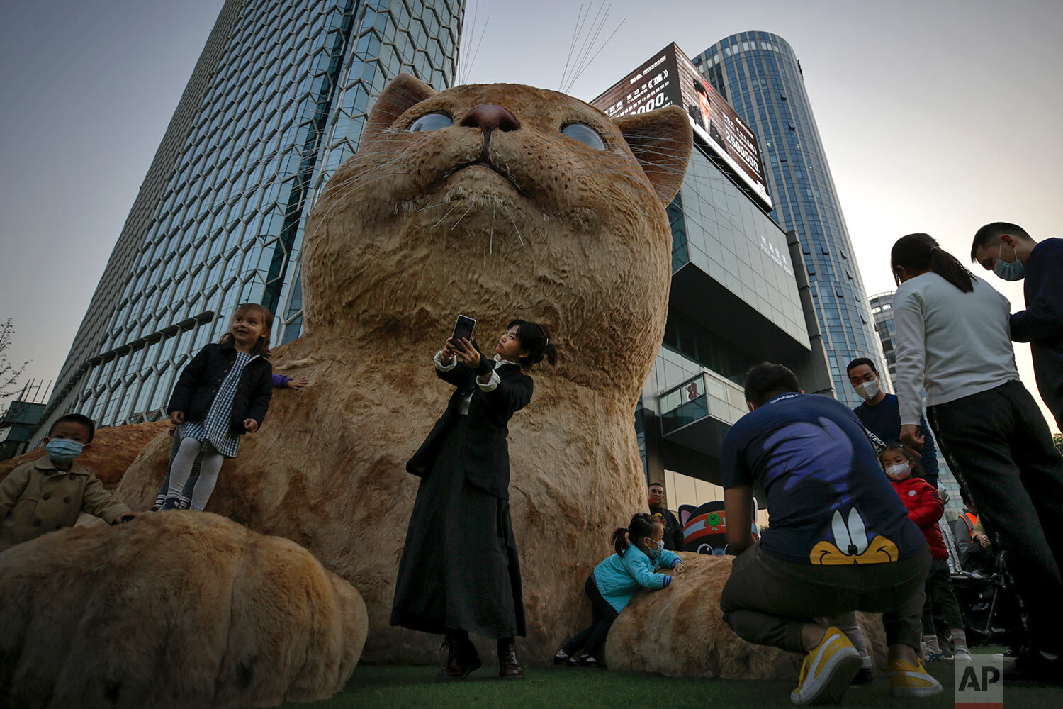  A woman takes a selfie as visitors wearing face masks to help curb the spread of the coronavirus gather near a giant cat structure on display at a commercial office building in Beijing, Sunday, Oct. 18, 2020. (AP Photo/Andy Wong) 