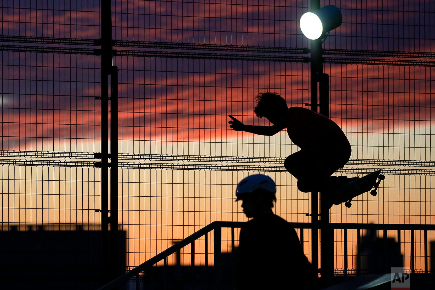  Skateboarders perform tricks silhouetted against the sunset colored sky on Sunday, Oct. 18, 2020, in Tokyo. (AP Photo/Kiichiro Sato) 