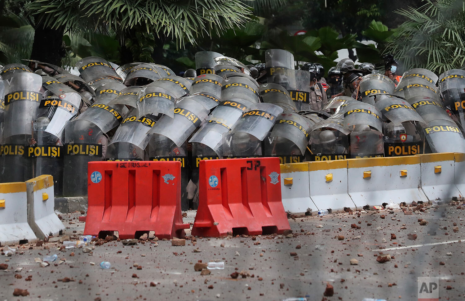  Riot police use their shields to form a defensive cover during a protest against the new Job Creation Law approved by Parliament, in Jakarta, Indonesia, Tuesday, Oct. 13, 2020. (AP Photo/Tatan Syuflana) 