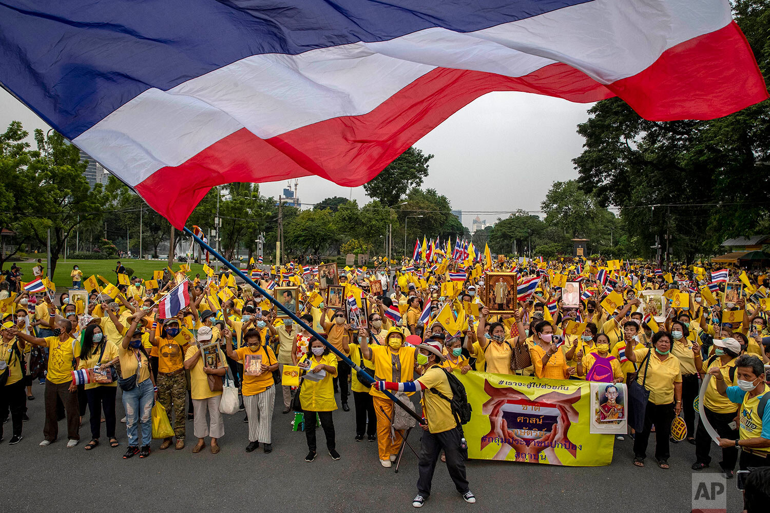  Supporters of the Thai monarchy display images of King Maha Vajiralongkorn, Queen Suthida, late King Bhumibol Adulyadej and wave a giant national flag during a rally at Lumphini park in central Bangkok, Thailand Tuesday, Oct. 27, 2020. (AP Photo/Gem