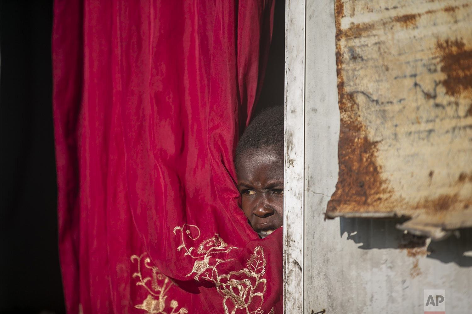  Jonelson Princeton, 7, who survived cholera as a newborn, peers out from inside his home which was once used as an office, on a former UN base where he lives with his parents and grandmother in Mirebalais, Haiti, Oct. 19, 2020. (AP Photo/Dieu Nalio 