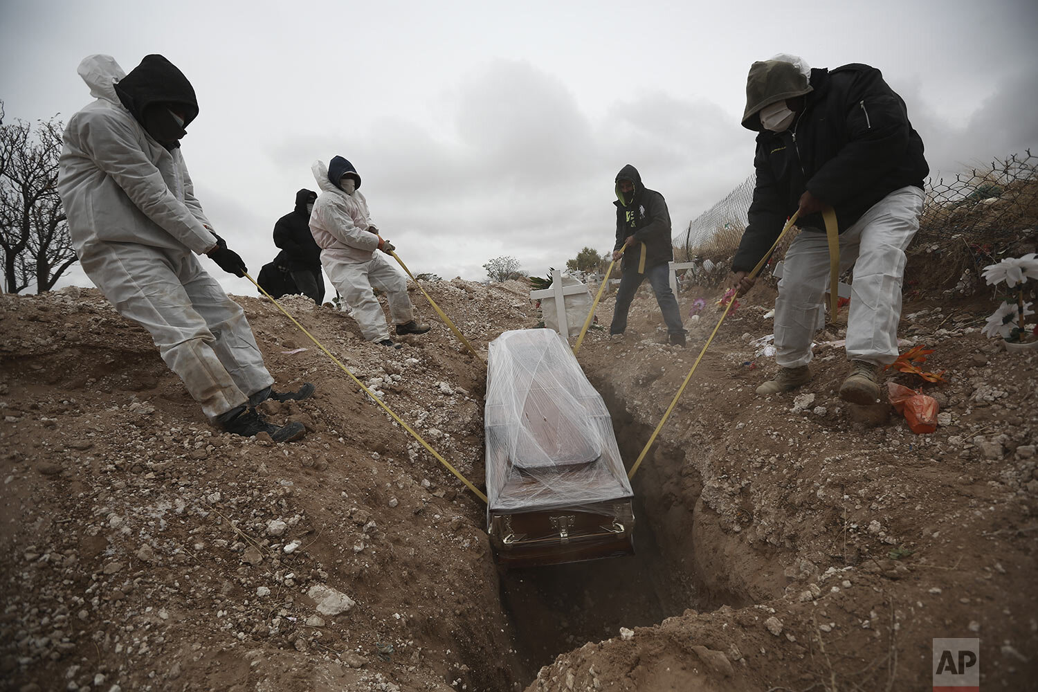  Workers wearing full protection gear amid the new coronavirus pandemic, lower a coffin into a grave in an area of the San Rafael municipal cemetery set apart for people who have died from COVID-19, in Ciudad Juarez, Mexico, Oct. 27, 2020. (AP Photo/