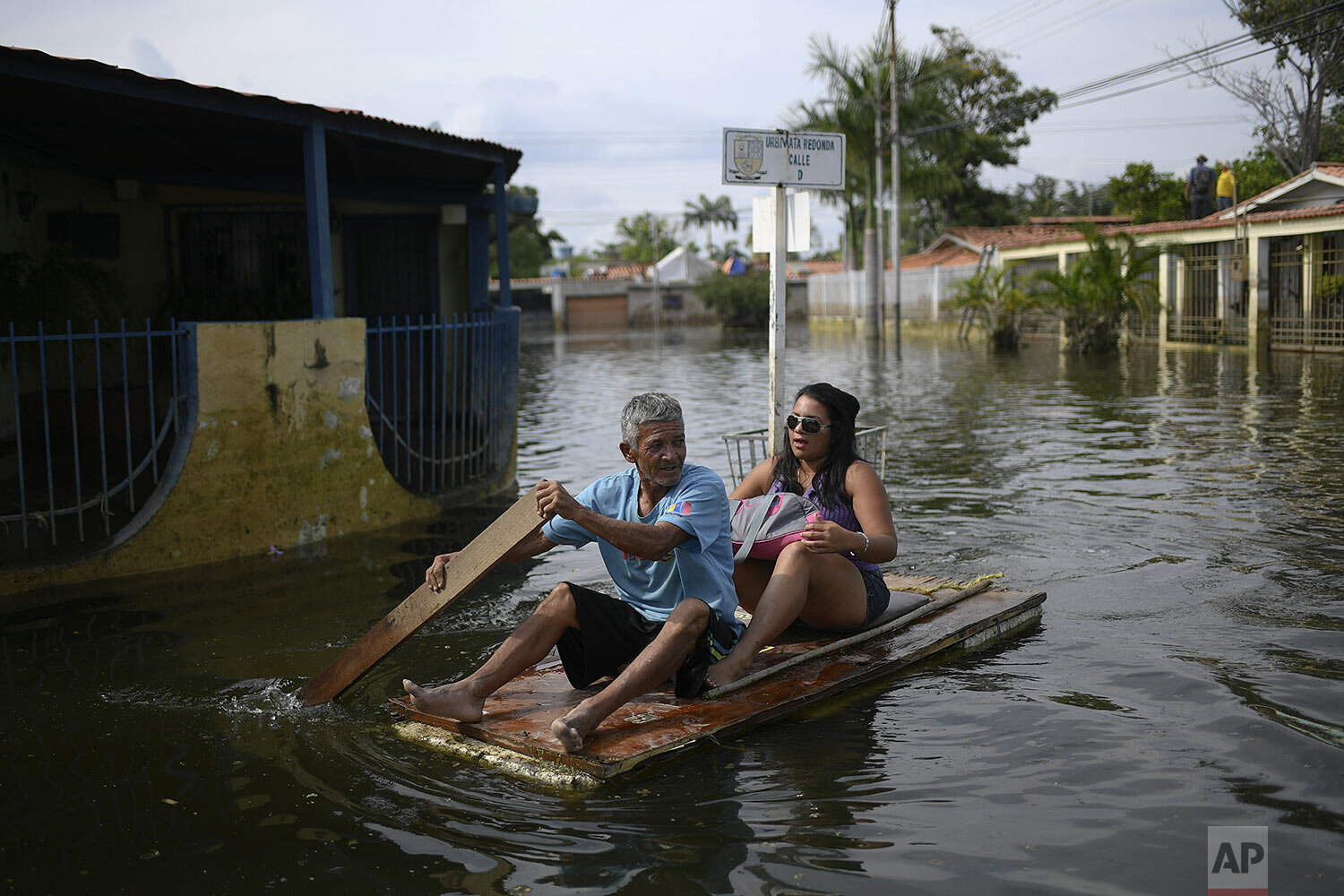  A man utilizes a door as a makeshift raft as he transports a woman through the inundated streets of the Mata Redonda neighborhood of Maracay, Venezuela, Oct. 21, 2020. (AP Photo/Matias Delacroix) 