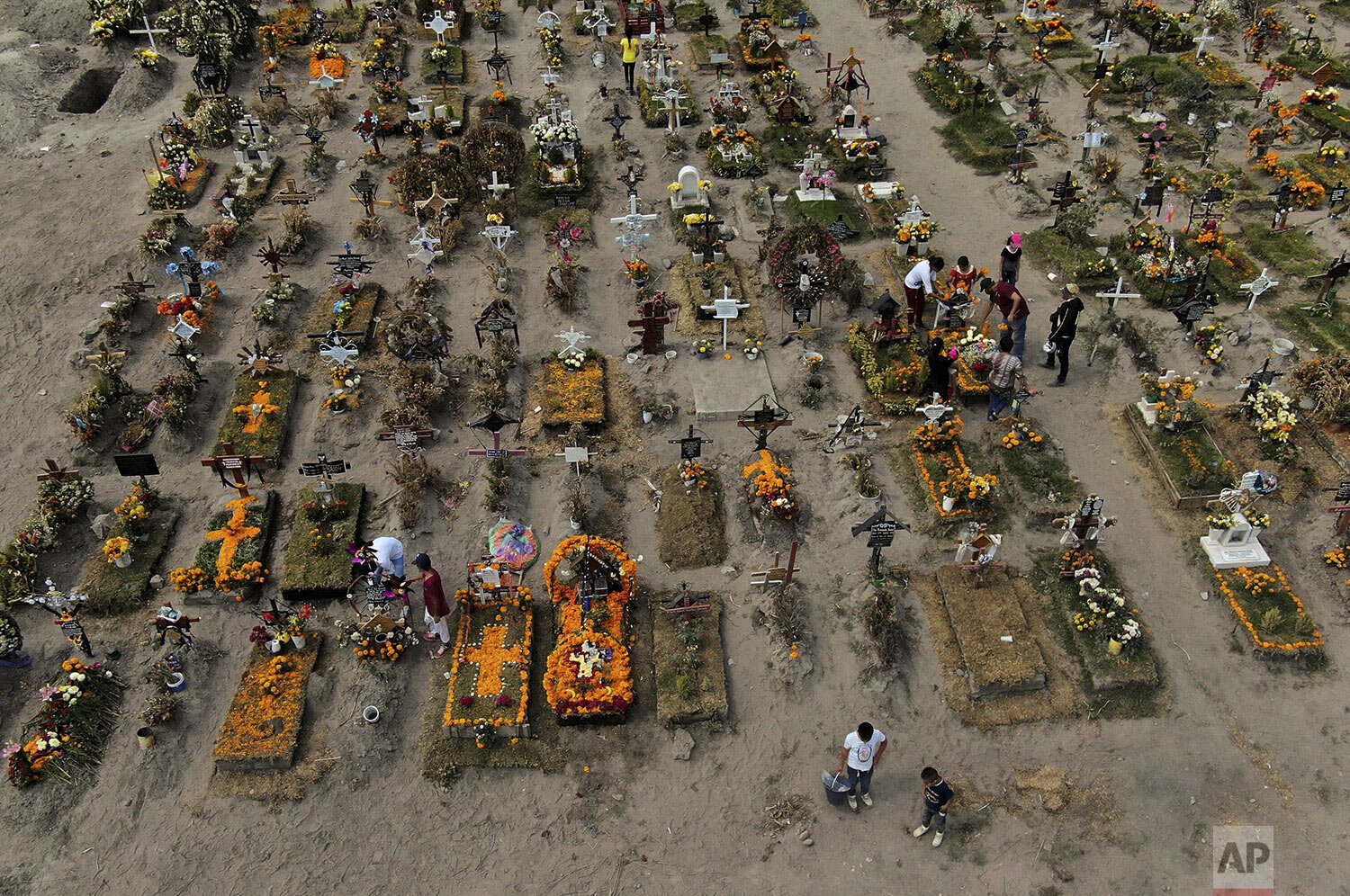  People visit the graves of their relatives buried at the Valle de Chalco municipal cemetery, some decorated ahead of the Day of the Dead holiday, on the outskirts of Mexico City, Oct. 29, 2020. (AP Photo/Fernando Llano) 