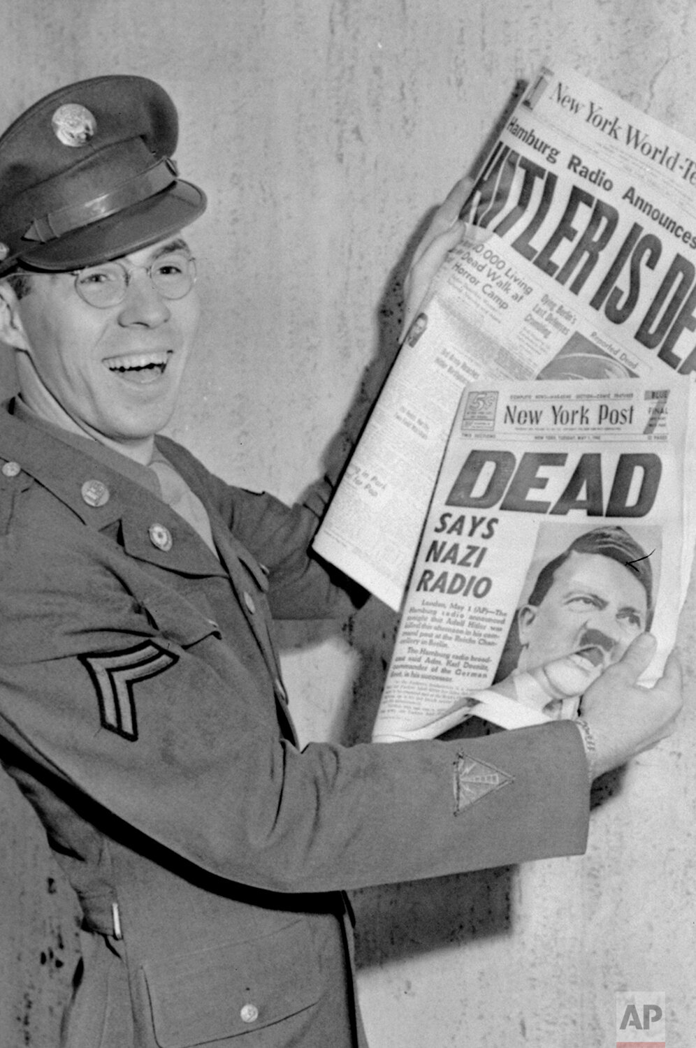  Cpl. William C. LaRue, of the Bronx, N.Y., displays the New York Post and the New York World Telegram proclaiming "Hitler is Dead," on May 1, 1945. (AP Photo) 