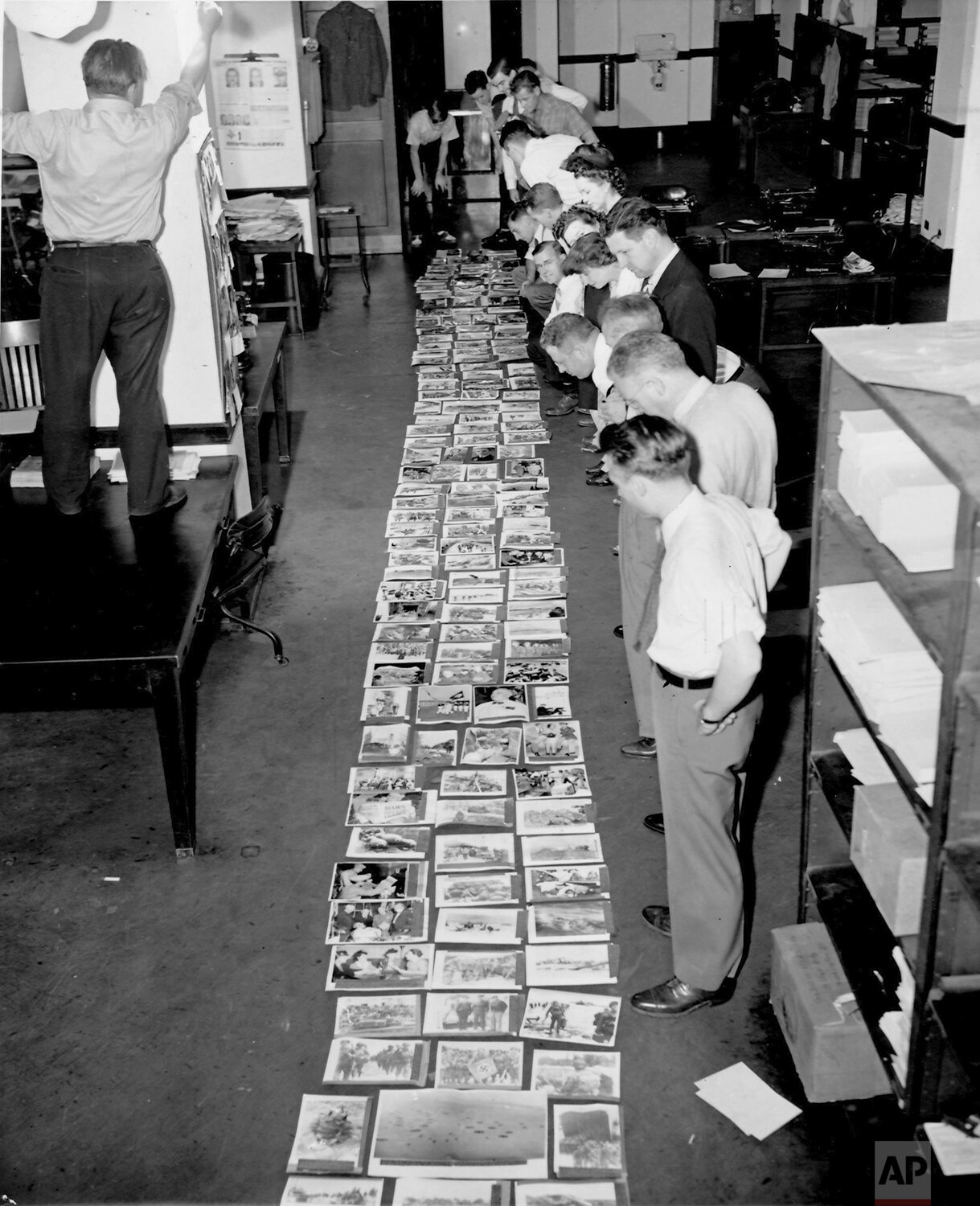  Staff in the AP's Washington Bureau view the layout of 153 pictures sent by Washington over Wirephoto during the first four and a half days of the D-Day invasion, starting June 6, 1944 through June 10, 3:30 P.M. During that same period all other poi