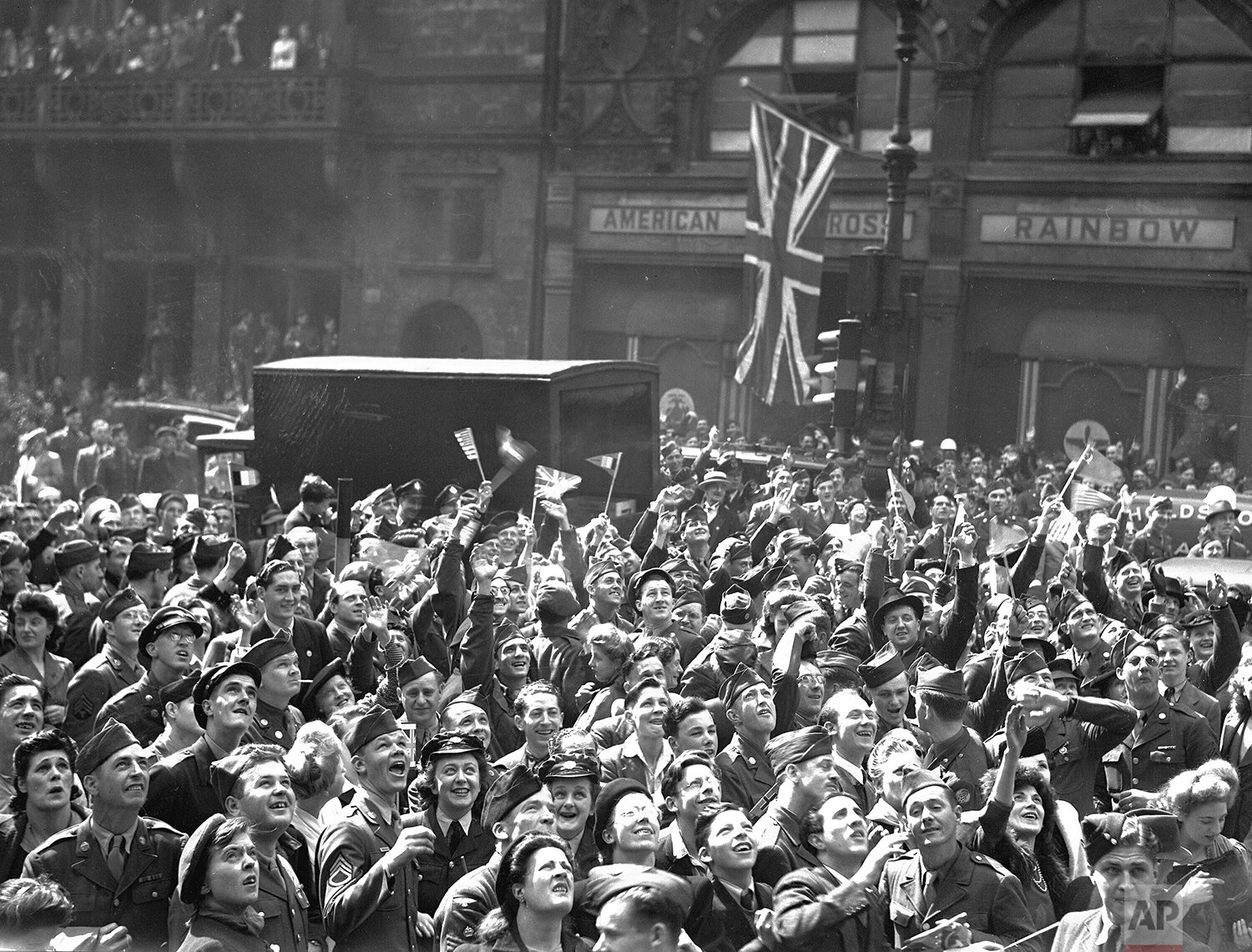  In this May 7, 1945 photo, British civilians and Allied service men and women gather, as part of a huge crowd, outside Rainbow Corner, the American Red Cross club, near Piccadilly Circus, London to hear the final announcement of Germany's surrender 