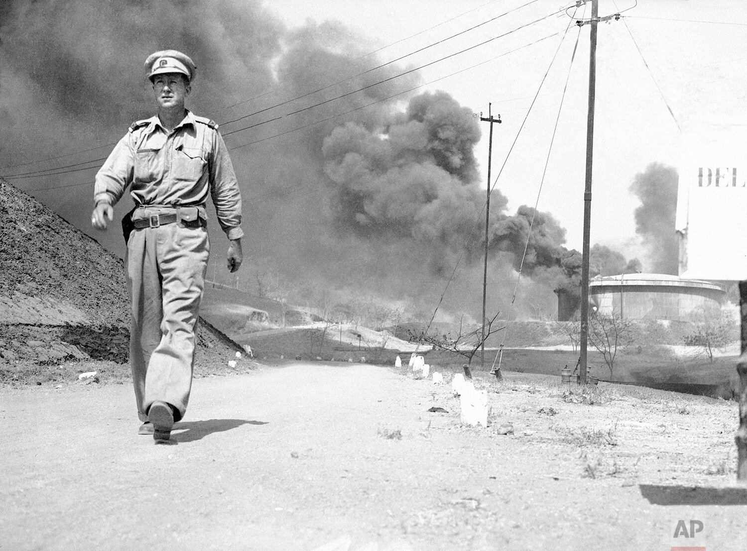  Daniel de Luce, Associated Press war correspondent, attached to the Chinese Army and the United States Air Force in China, walks through a street in Yenangyaung, Burma, July 20, 1942, before Japanese force invaded the city. Dark smoke in the backgro