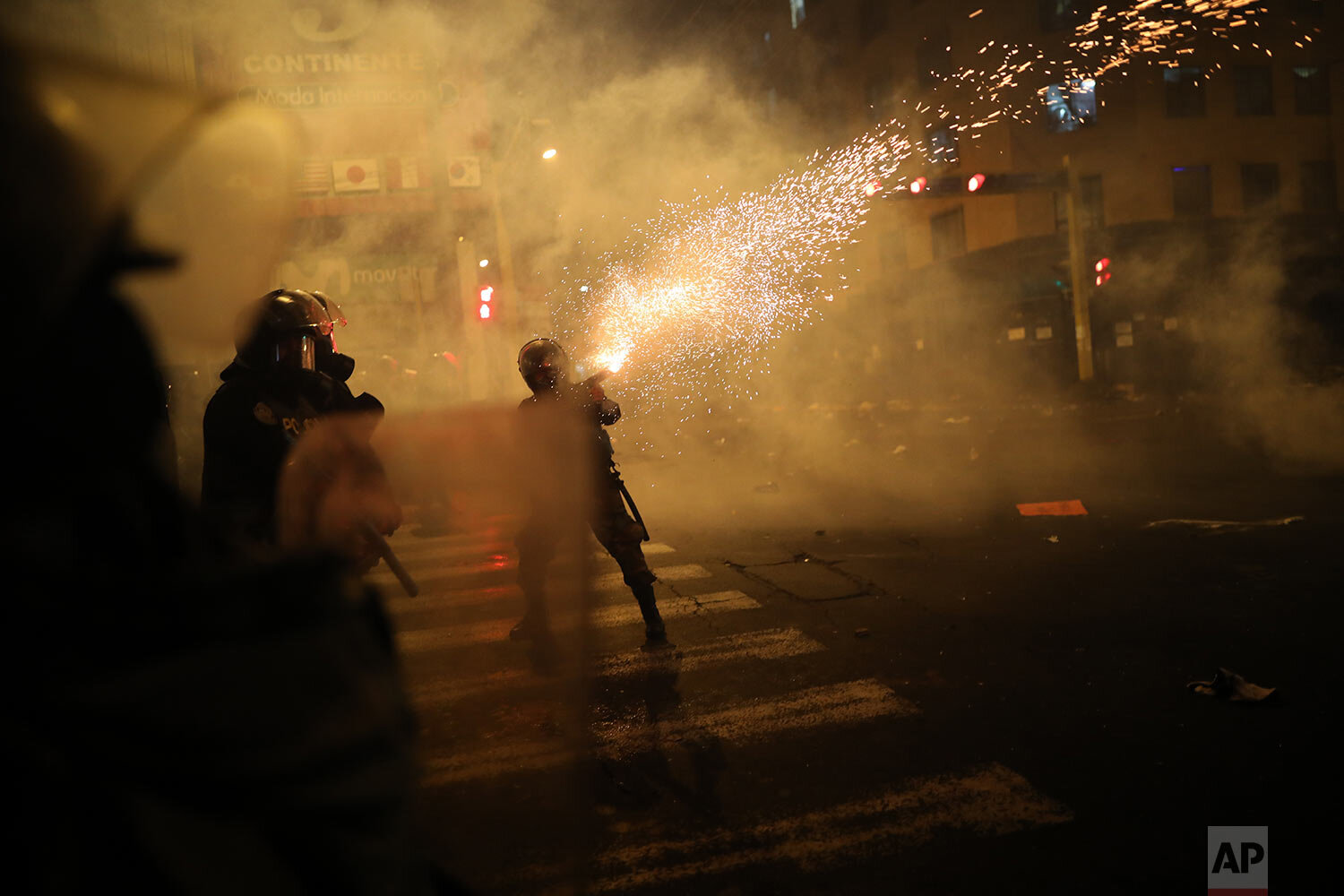  A policeman launches tear gas to disperse protesters attempting to march to Congress in a demonstration against the removal of President Martin Vizcarra, in Lima, Peru, Thursday, Nov. 12, 2020.  (AP Photo/Rodrigo Abd) 