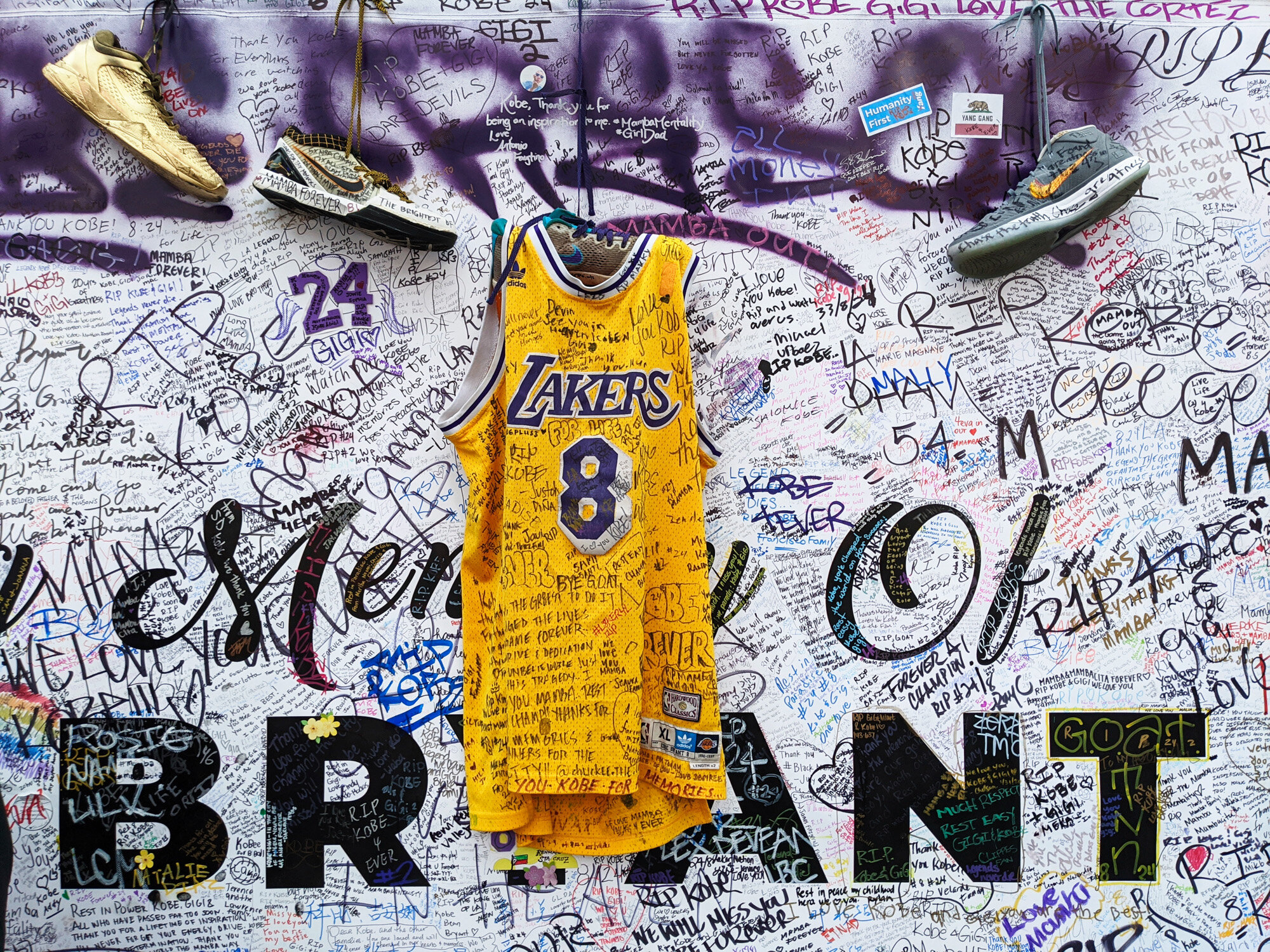  Sneakers and a Los Angeles Lakers jersey with the number 8 worn by NBA star Kobe Bryant hang at a memorial for Bryant in Los Angeles on Feb. 2, 2020, a week after he was killed in a helicopter crash. (AP Photo/Damian Dovarganes) 