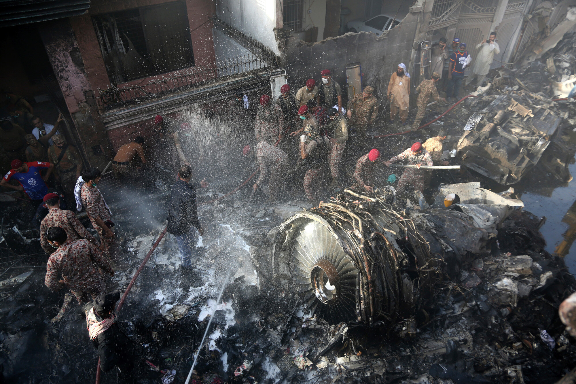 Rescue workers and local residents search for survivors in the wreckage of a plane that crashed with nearly 100 people onboard in a residential area of Karachi, Pakistan, on May 22, 2020. (AP Photo/Fareed Khan)