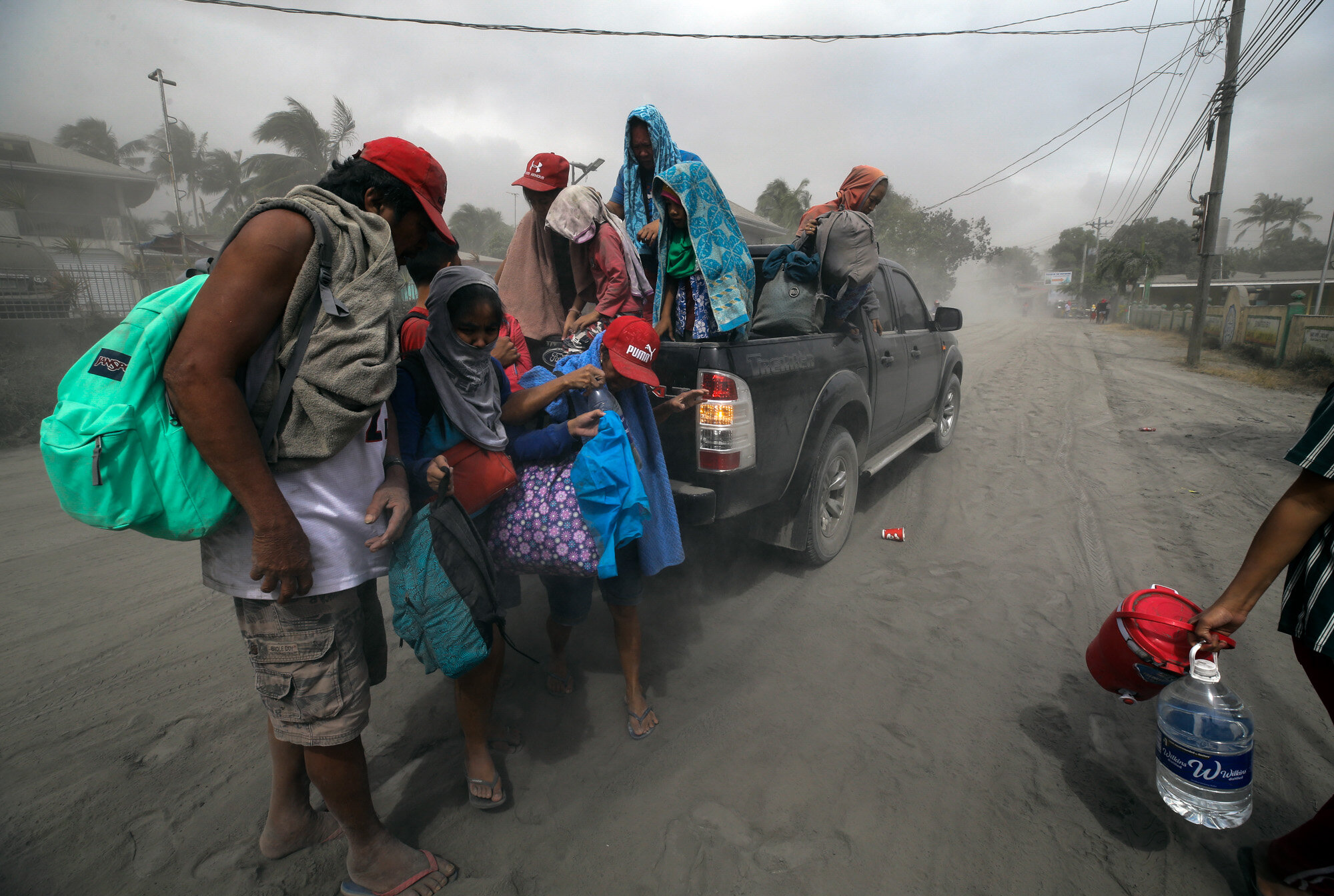 A family evacuates to safer ground as the Taal Volcano spews ash in Lemery, Batangas, southern Philippines on Jan. 13, 2020. (AP Photo/Aaron Favila)