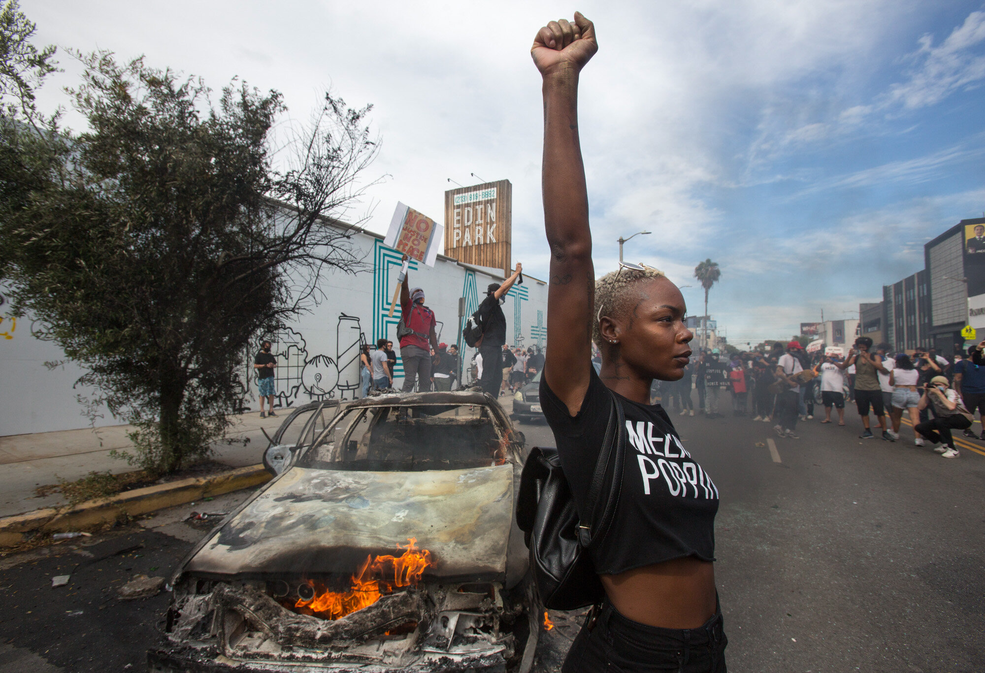 A protester poses for photos next to a burning police vehicle in Los Angeles on May 30, 2020, during a demonstration over the death of George Floyd, a Black man who died in Minneapolis after a white police officer pressed a knee into his neck for several minutes. (AP Photo/Ringo H.W. Chiu)