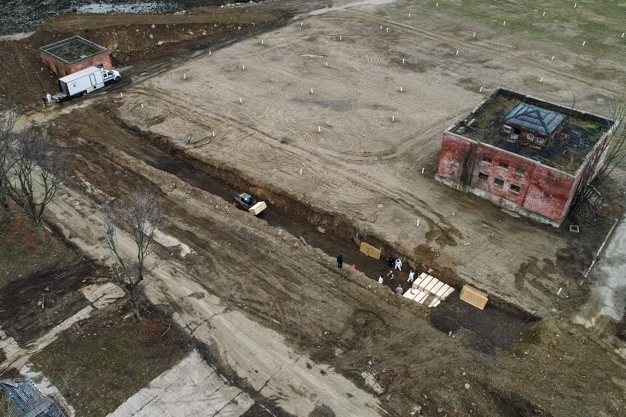 Workers wearing personal protective equipment bury bodies in a trench on Hart Island in the Bronx borough of New York on April 9, 2020. Hart Island is a strip of land in Long Island Sound that has long served as the city’s potter’s field. (AP Photo/John Minchillo)