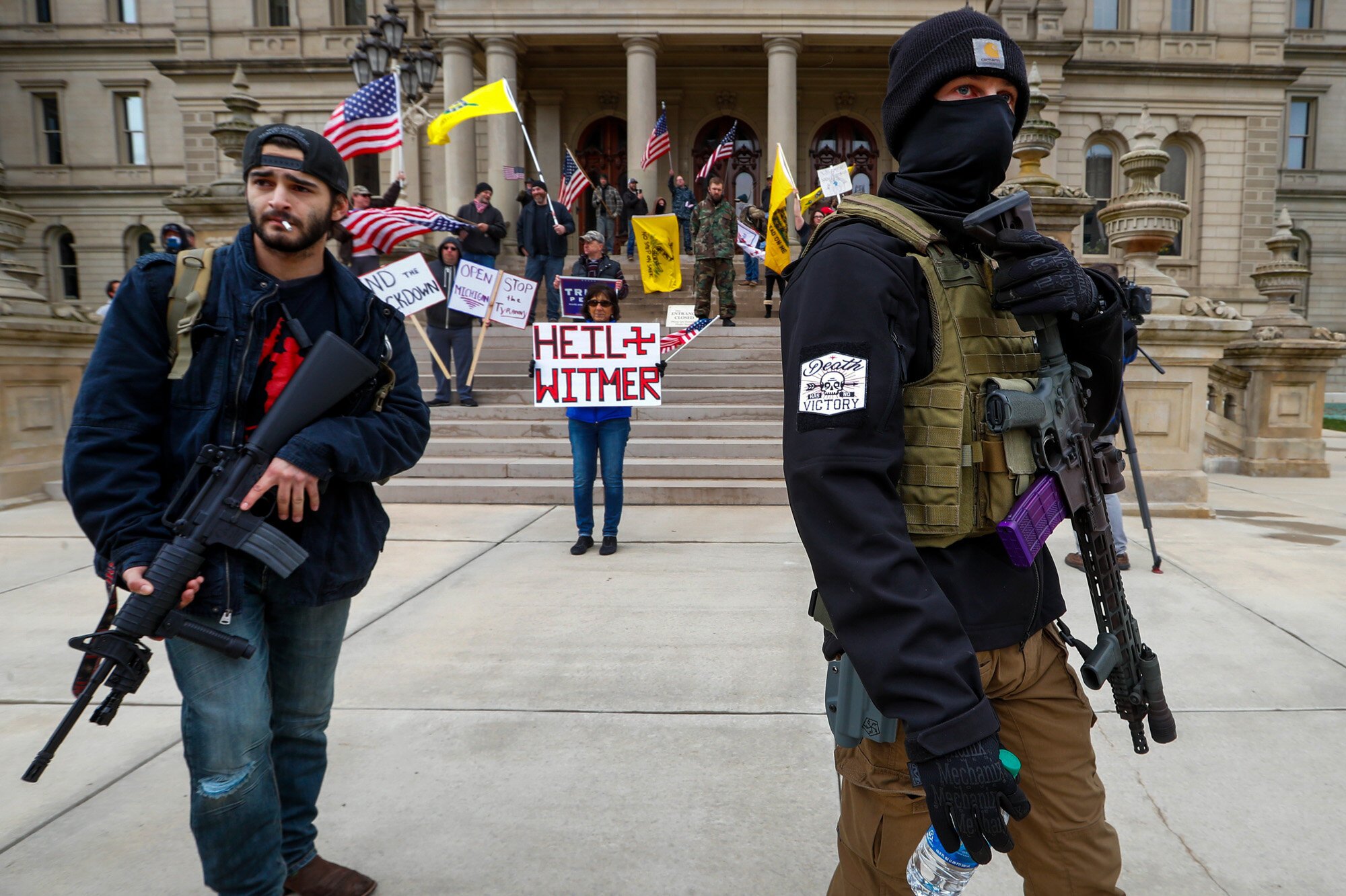  Men carry rifles near the steps of the State Capitol building in Lansing, Mich., on April 15, 2020, during a protest over Michigan Gov. Gretchen Whitmer's orders to keep people at home and businesses locked during the coronavirus outbreak. (AP Photo