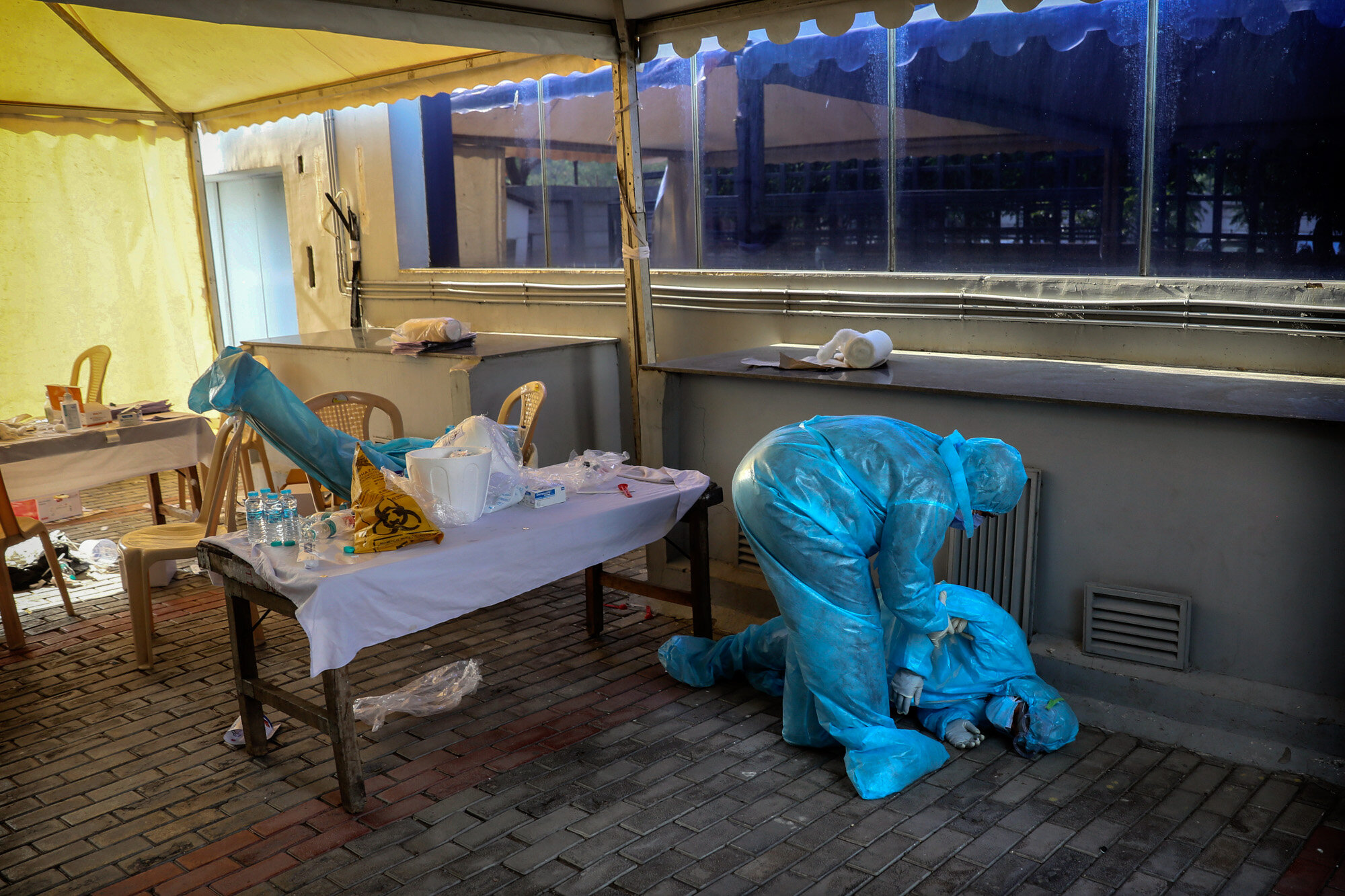 A health worker tends to her colleague, who fainted due to exhaustion at a COVID-19 testing camp in New Delhi, India on April 27, 2020. (AP Photo/Manish Swarup)