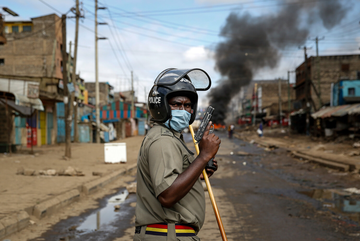  A police officer holds a pistol during clashes with protesters near a barricade of burning tires in the Kariobangi slum of Nairobi, Kenya, on May 8, 2020. Hundreds of protesters blocked one of the capital's major highways to protest government demolitions of the homes of more than 7,000 people, causing many to sleep out in the rain and cold because of restrictions on movement due to the coronavirus. (AP Photo/Brian Inganga) 