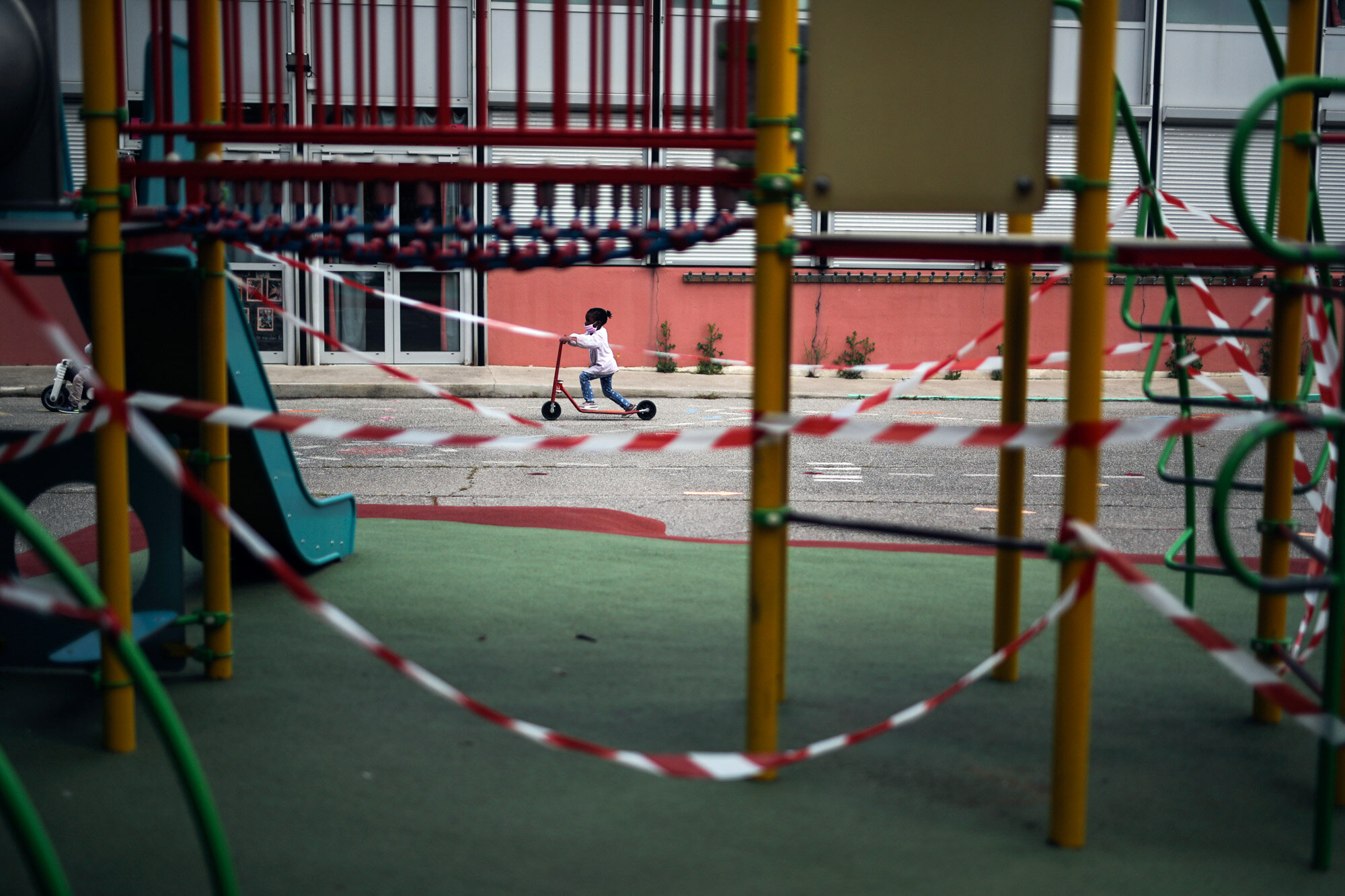 A girl rides a scooter past the Saint-Tronc Castelroc primary school playground, closed to prevent the spread of the coronavirus, in Marseille, France, on May 14, 2020. (AP Photo/Daniel Cole)