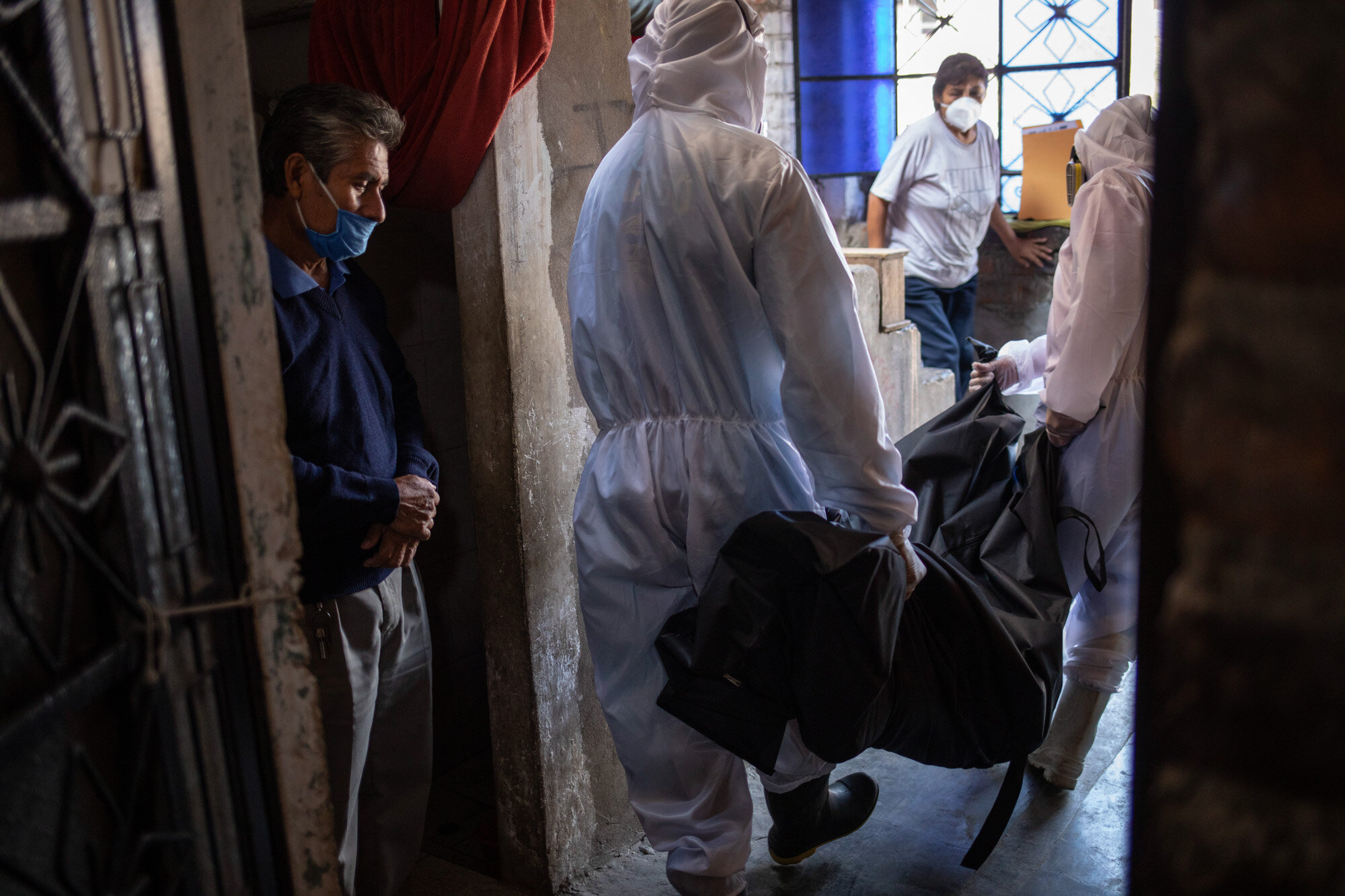 Teodoro Mejia, left, watches workers from the Piedrangel funeral home remove the body of his wife, Berta Cusi Palomino, from their home in Lima, Peru, May 14, 2020. Palomino was believed to have died from COVID-19. (AP Photo/Rodrigo Abd)