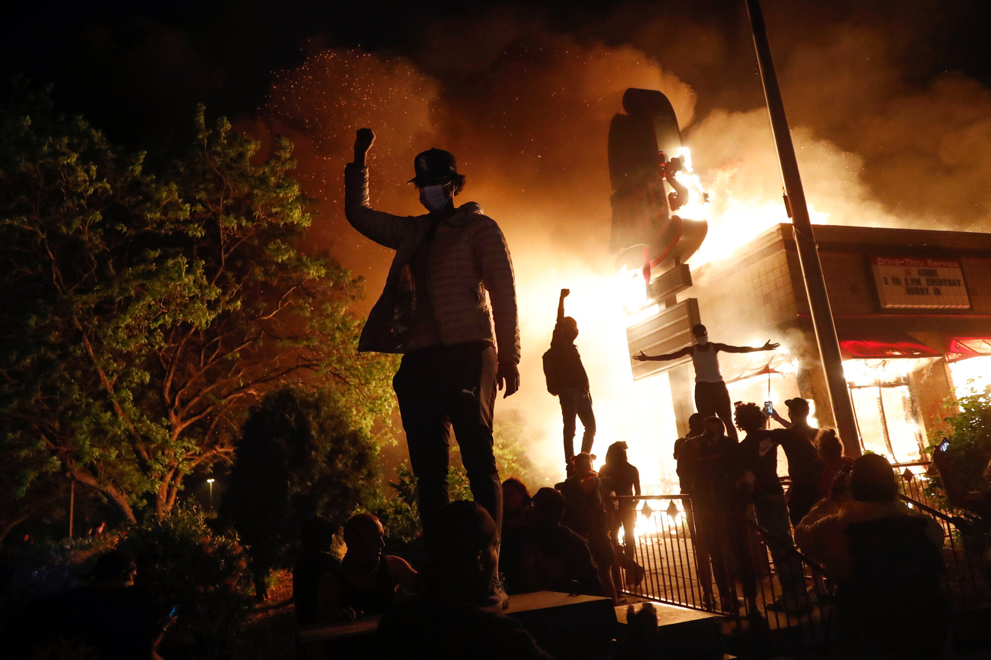 People demonstrate outside a burning Arby’s fast food restaurant on May 29, 2020, in Minneapolis during a protest over the death of George Floyd, a Black man who died after a white Minneapolis police officer pressed a knee into his neck for several minutes. (AP Photo/John Minchillo)