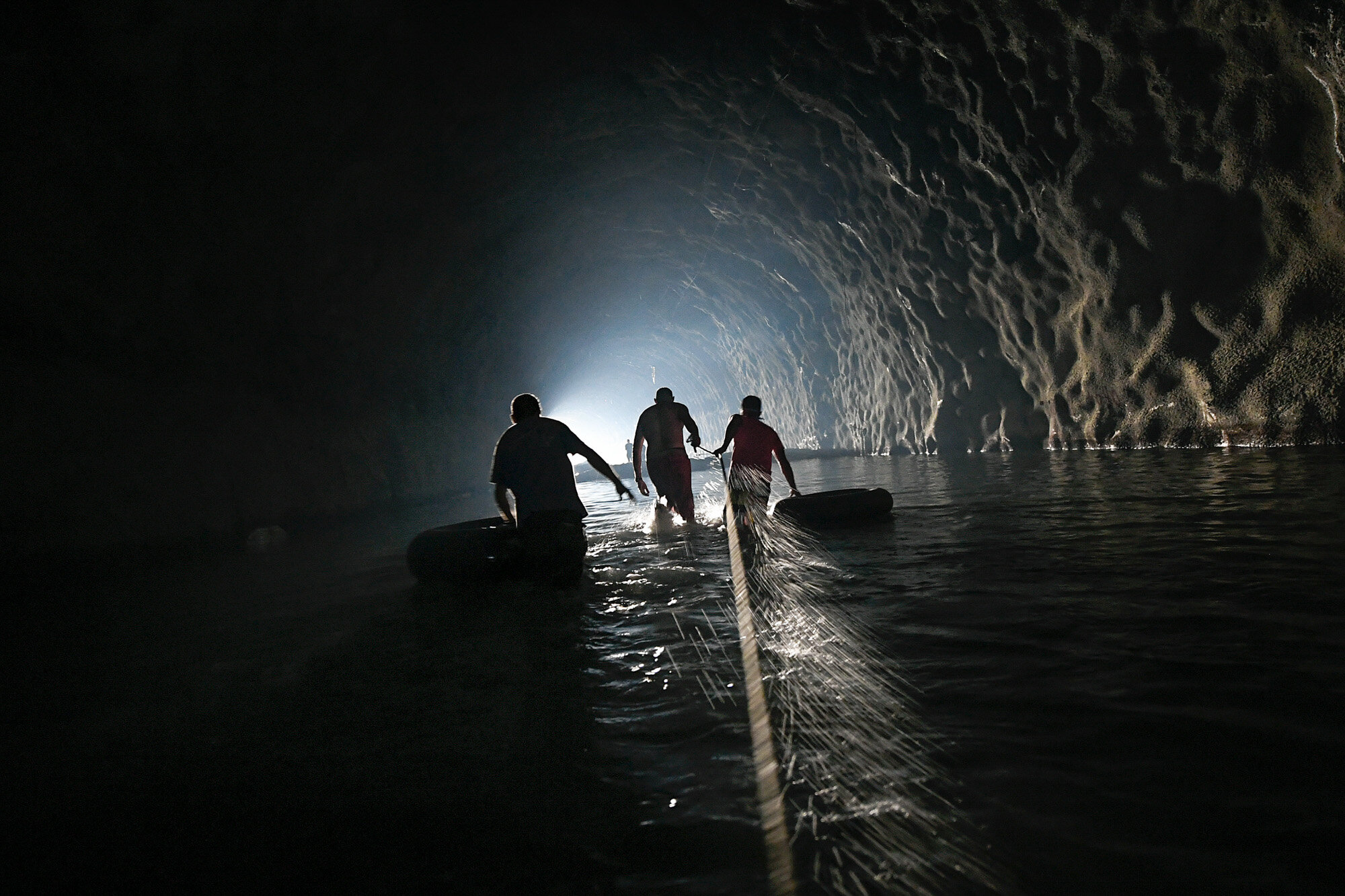  Men with inner tubes wade through an abandoned highway tunnel with the aid of a safety line as they work to repair a self-created water system in the Esperanza neighborhood of Caracas, Venezuela, on June 11, 2020. Water service in Venezuela has gott