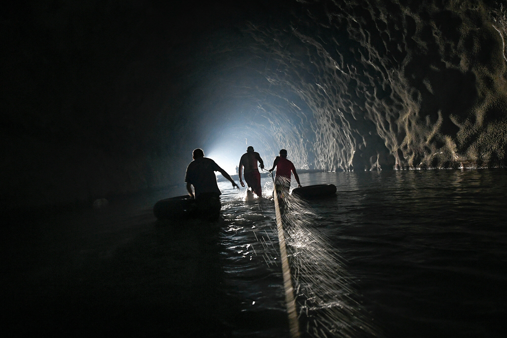Men with inner tubes wade through an abandoned highway tunnel with the aid of a safety line as they work to repair a self-created water system in the Esperanza neighborhood of Caracas, Venezuela, on June 11, 2020. Water service in Venezuela has gotten so bad that poor neighborhoods have started to rig private water systems or hand dig shallow wells. (AP Photo/Matias Delacroix)