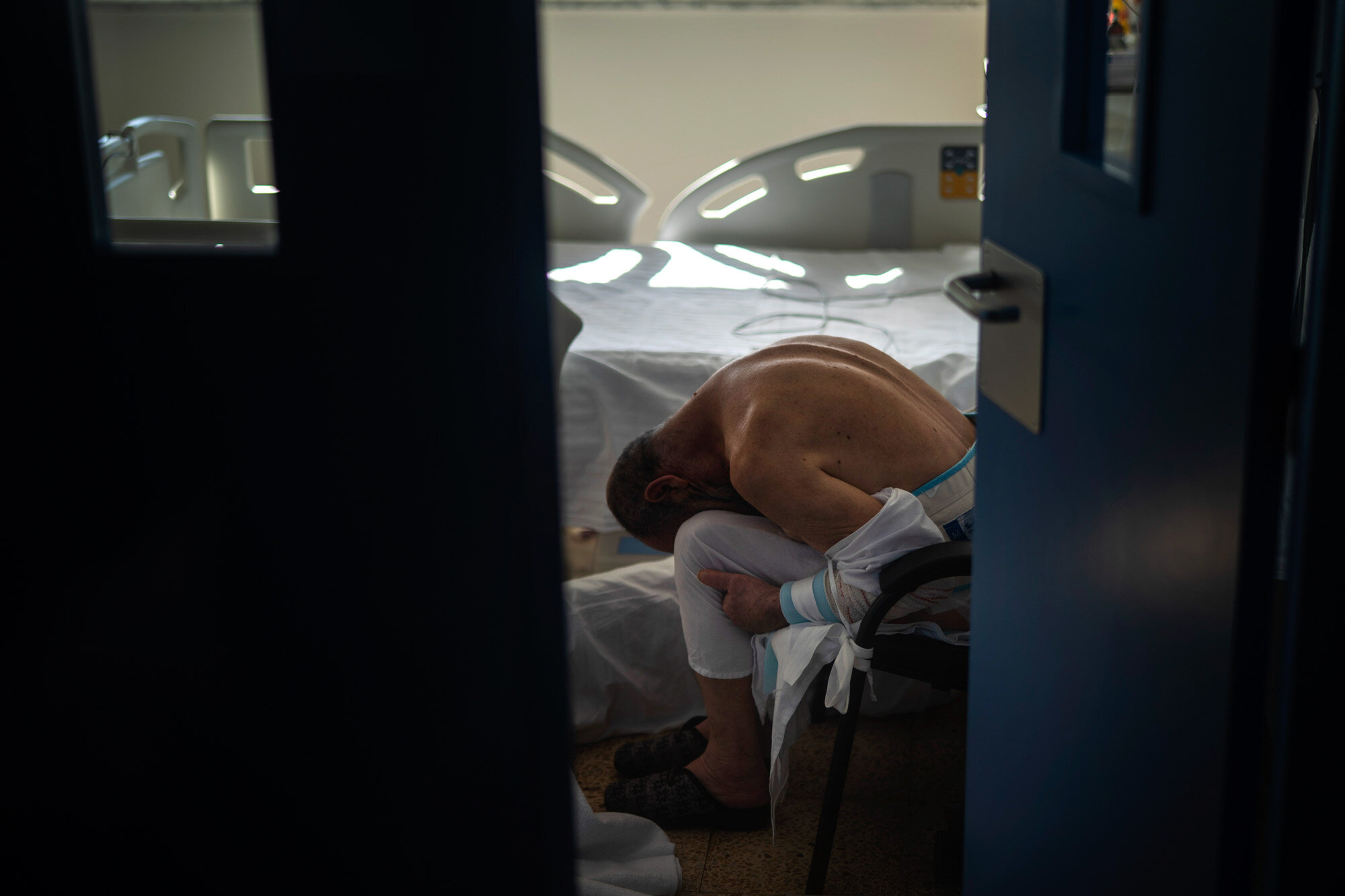 A patient rests in a chair next to his bed at the COVID-19 ward at a hospital in Barcelona, Spain, on Nov. 18, 2020. (AP Photo/Emilio Morenatti)
