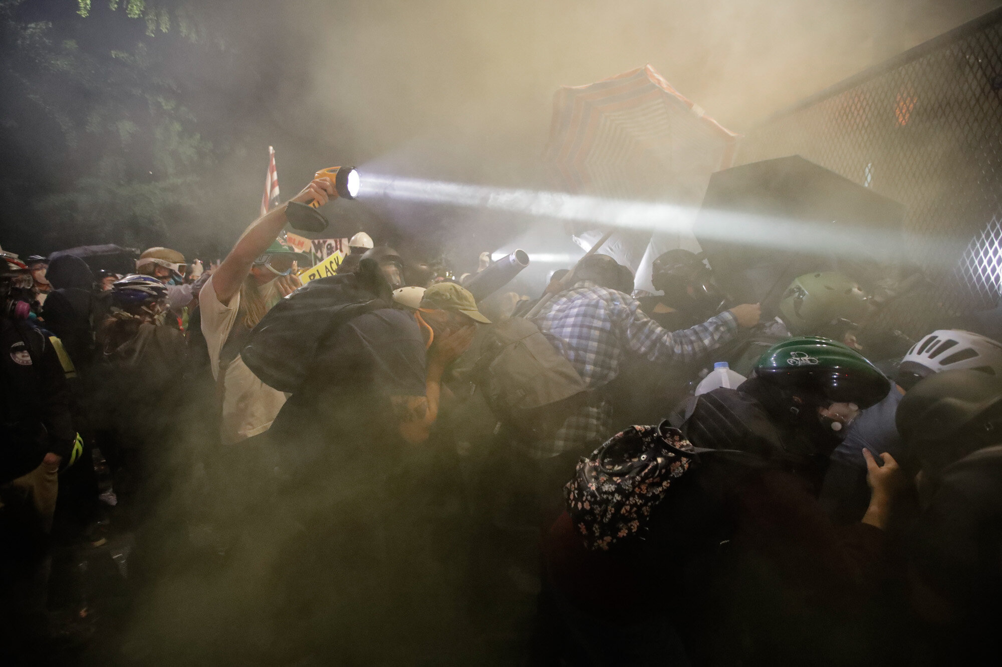 Demonstrators push on a fence as tear gas is deployed during a Black Lives Matter protest at the Mark O. Hatfield United States Courthouse in Portland, Ore., on July 25, 2020. (AP Photo/Marcio Jose Sanchez)