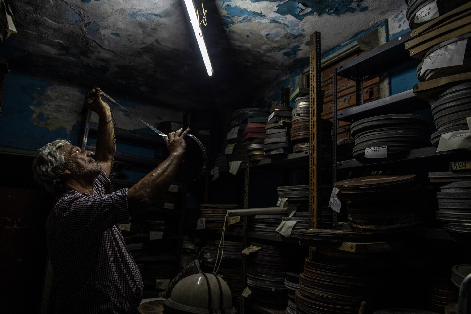 Projector operator Pavlos Lepeniotis checks the quality of movie film inside a warehouse at the Zephyros open-air cinema, which specializes in films from past decades, in Ano Petralona, central Athens, on June 3, 2020. Lepeniotis has worked in movie theaters since age 12. (AP Photo/Petros Giannakouris)