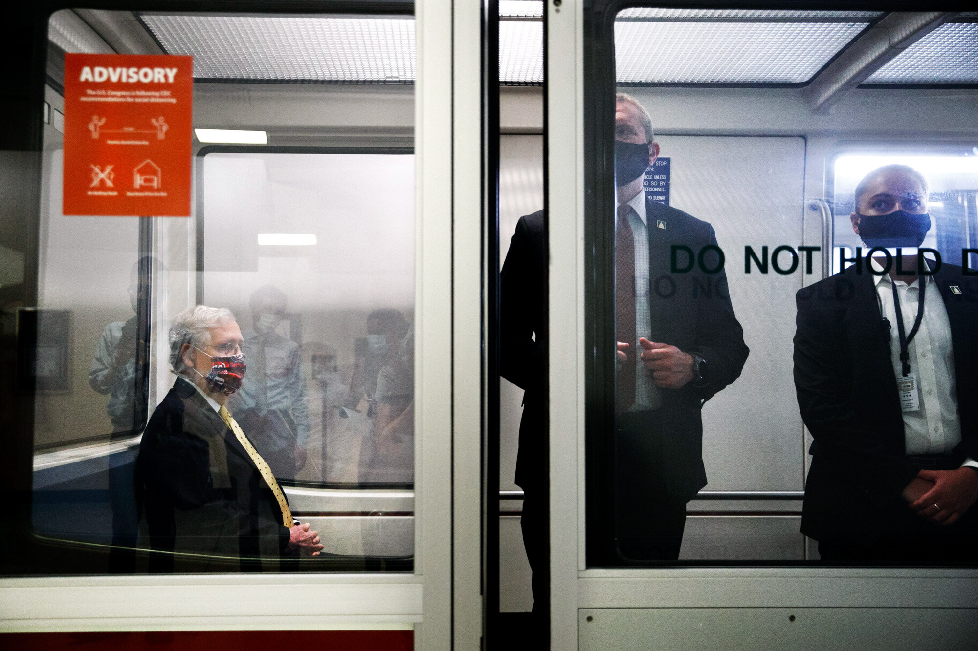 Senate Majority Leader Mitch McConnell of Kentucky, left, wears a mask for protection against the coronavirus, along with members of security, as he rides the Senate Subway between meetings on Capitol Hill in Washington on July 21, 2020. (AP Photo/Jacquelyn Martin)