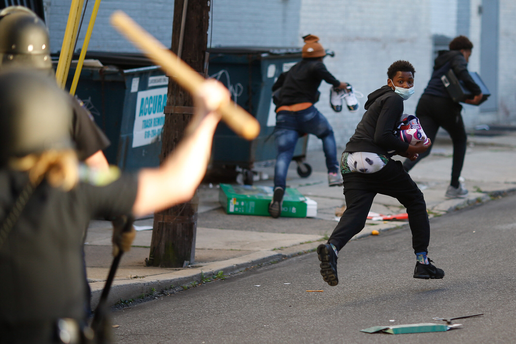  People flee from police officers after running out the back of a store carrying shoes in Upper Darby, Pa., on May 31, 2020, following protests over the death of George Floyd, a Black man who was killed by a police officer in Minneapolis on May 25. (