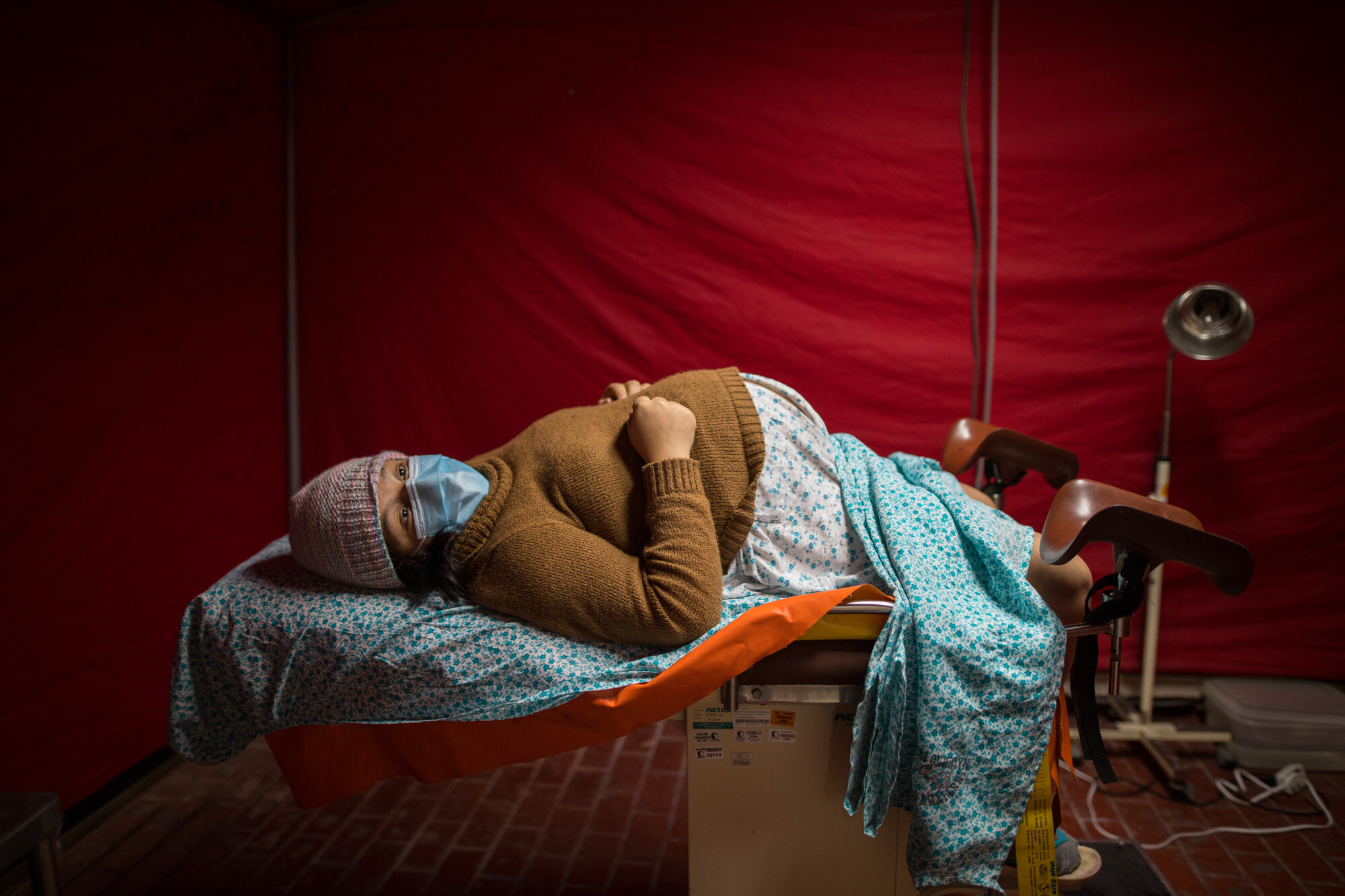  Olinda Tafur, 20, lies on an examination table as she waits to be seen by an obstetrician inside a tent set up in the emergency area of the National Perinatal and Maternal Institute to receive women in labor who are infected with COVID-19, in Lima, 