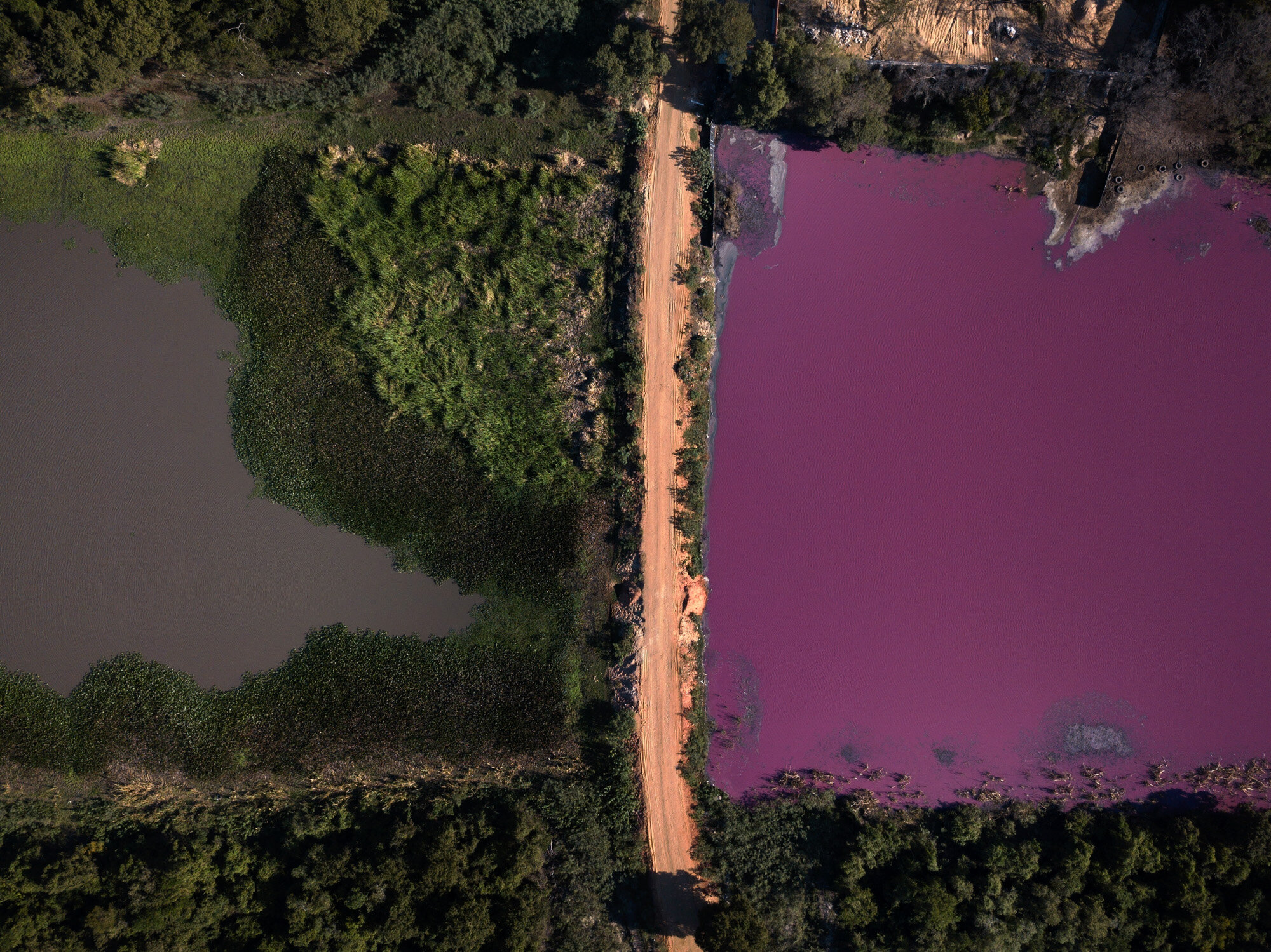  A road divides the Cerro Lagoon, where the water at right is colored and the Waltrading S.A. tannery stands on the bank, top right, in Limpio, Paraguay, on Aug. 5, 2020. According to Francisco Ferreira, a technician at the National University Multid