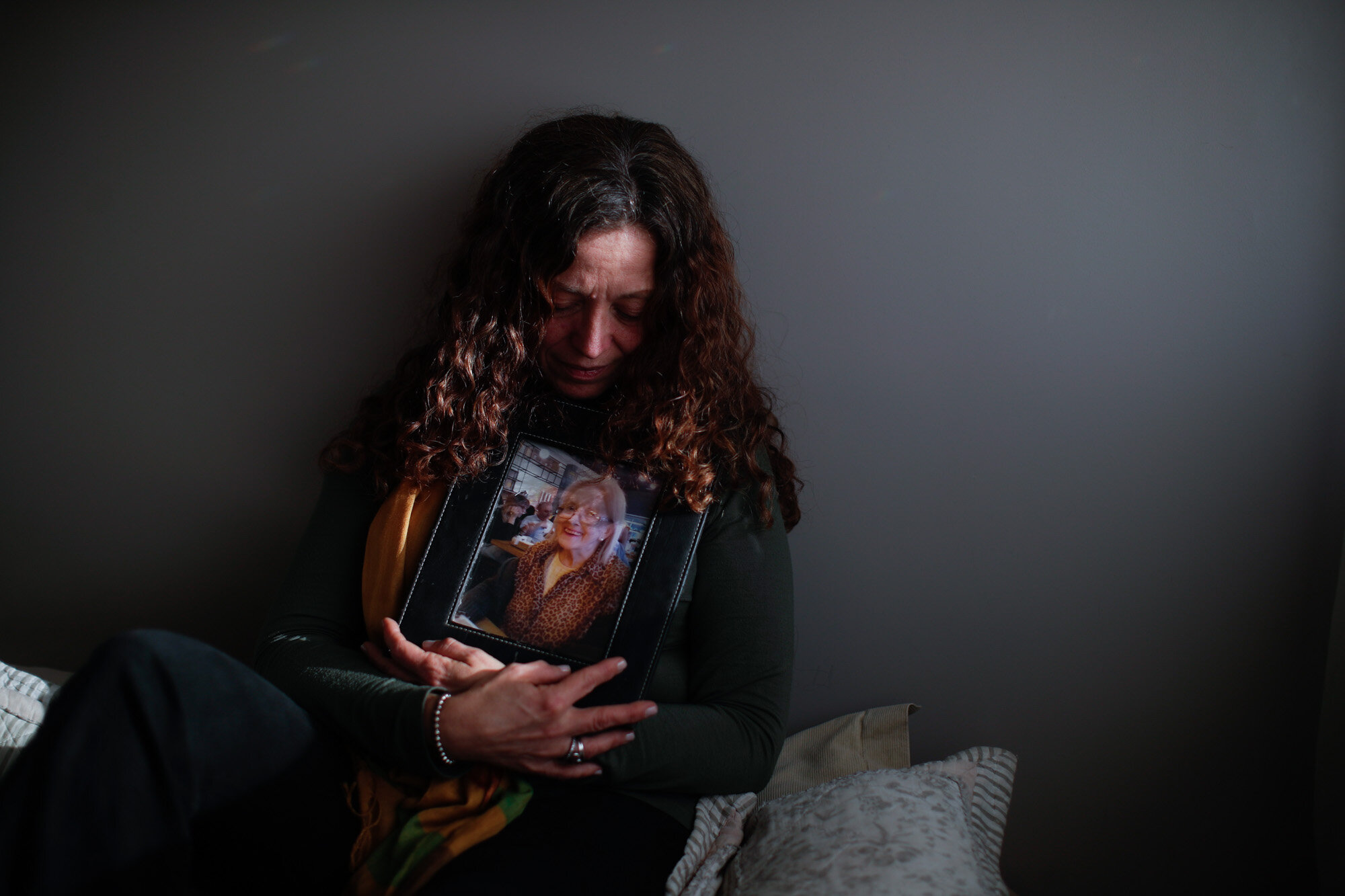 Fernanda Mariotti poses for a photo with a picture of her mother, Martha Pedrotti, who died of COVID-19, at her home in Buenos Aires, Argentina, on Aug. 11, 2020. Although Mariotti insisted on seeing her mother at the hospital, the doctor refused to allow it. (AP Photo/Natacha Pisarenko)