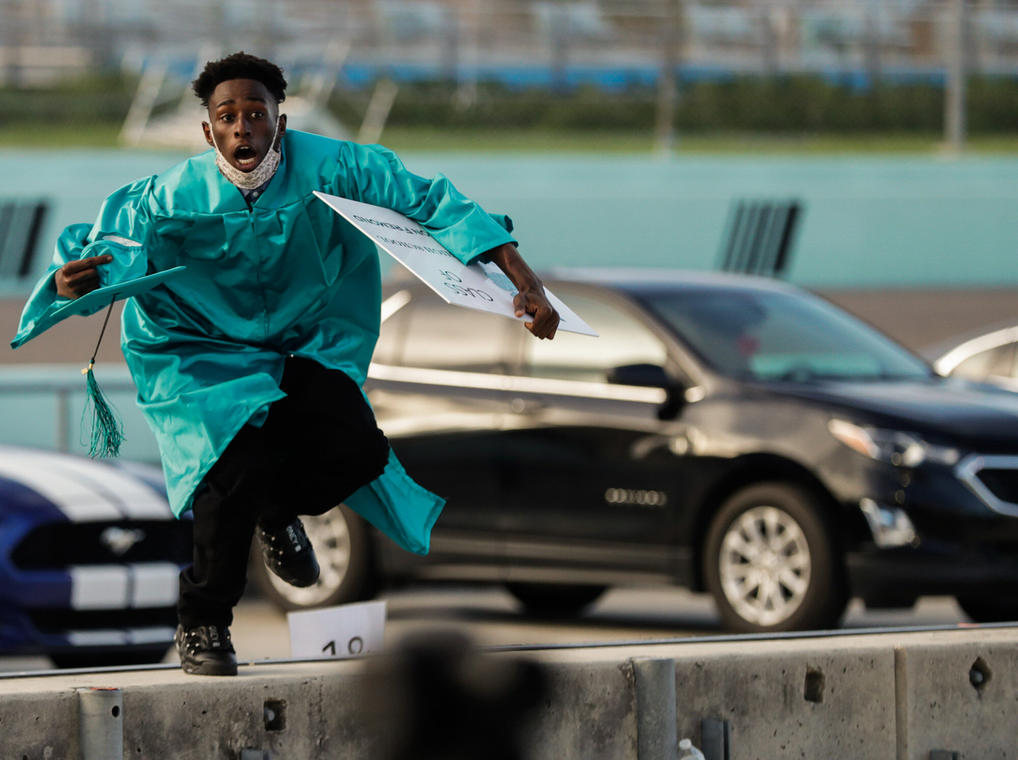 Richardson Fremond leaps over a wall as he runs to collect an award during the Chambers High School graduation ceremony at Homestead-Miami Speedway in Homestead, Fla., on June 23, 2020. The ceremony was held at the race track to enable social distancing during the coronavirus pandemic and the 41 seniors who graduated crossed the start-finish line to receive their diplomas. (AP Photo/Wilfredo Lee)