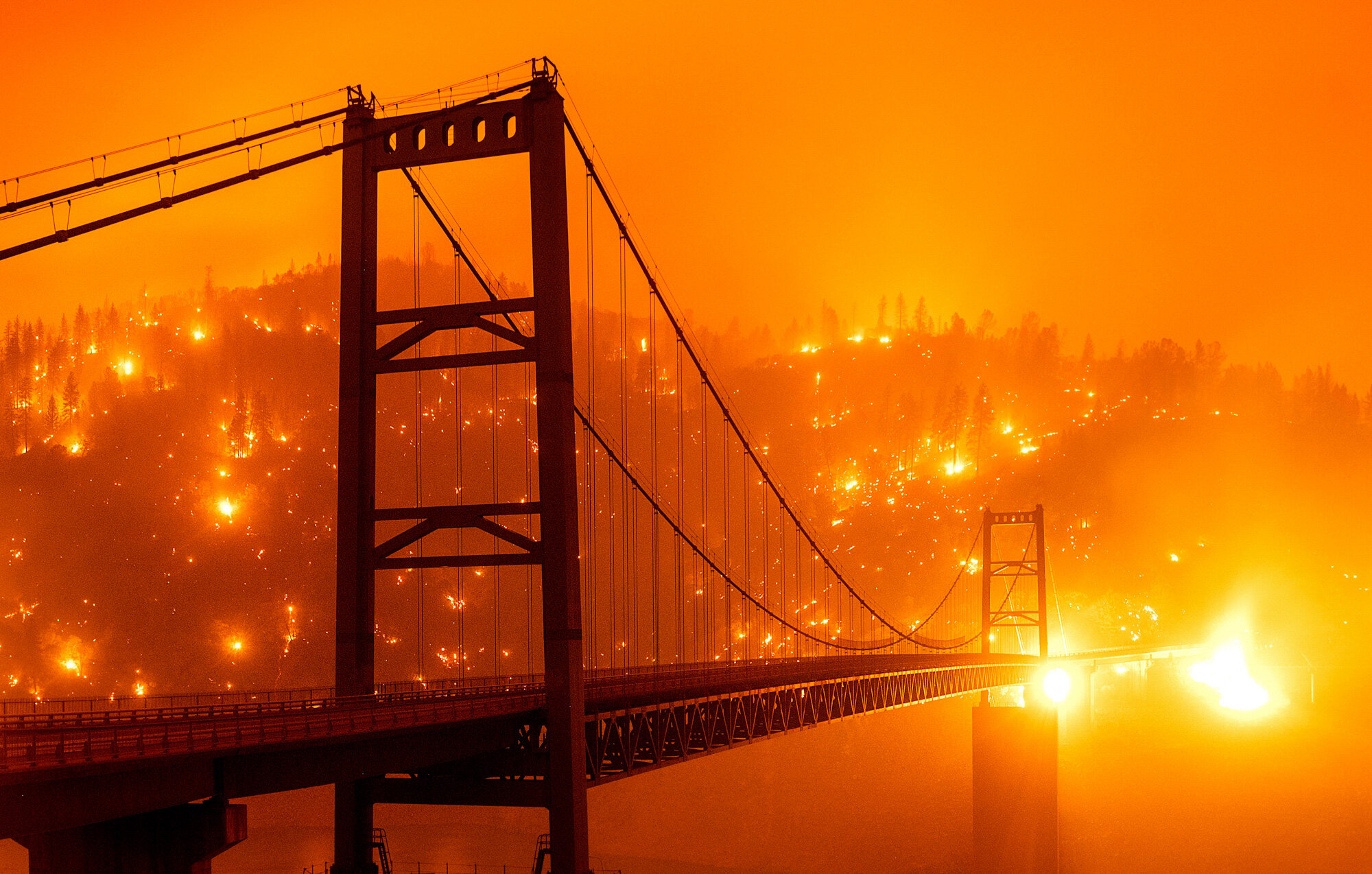Embers light up a hillside behind the Bidwell Bar Bridge on Sept. 9, 2020, as the Bear Fire burns in Oroville, Calif., in this photo taken with a slow shutter speed. (AP Photo/Noah Berger)