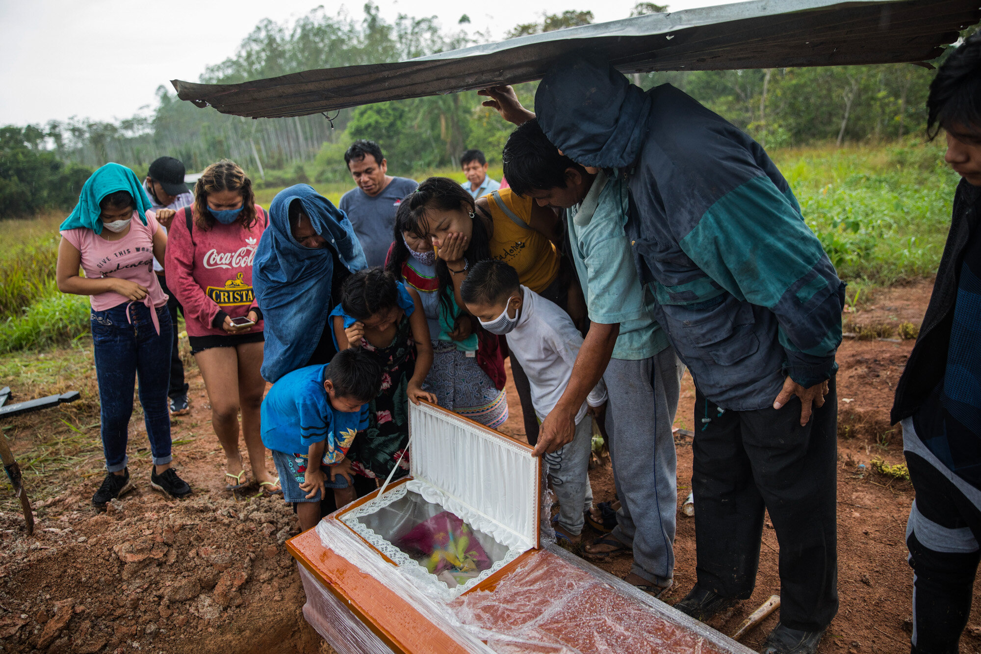 Family members peer into the coffin that contains the remains of Manuela Chavez, who died from symptoms related to the coronavirus at the age of 88, during a burial service in the Shipibo indigenous community of Pucallpa, in Peru's Ucayali region, on Aug. 31, 2020. (AP Photo/Rodrigo Abd)