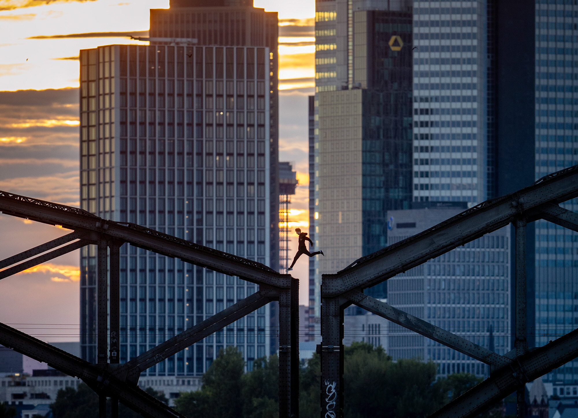 A parkour runner jumps on a railway bridge with the buildings of the banking district in background in Frankfurt, Germany, on Sept. 9, 2020. (AP Photo/Michael Probst)
