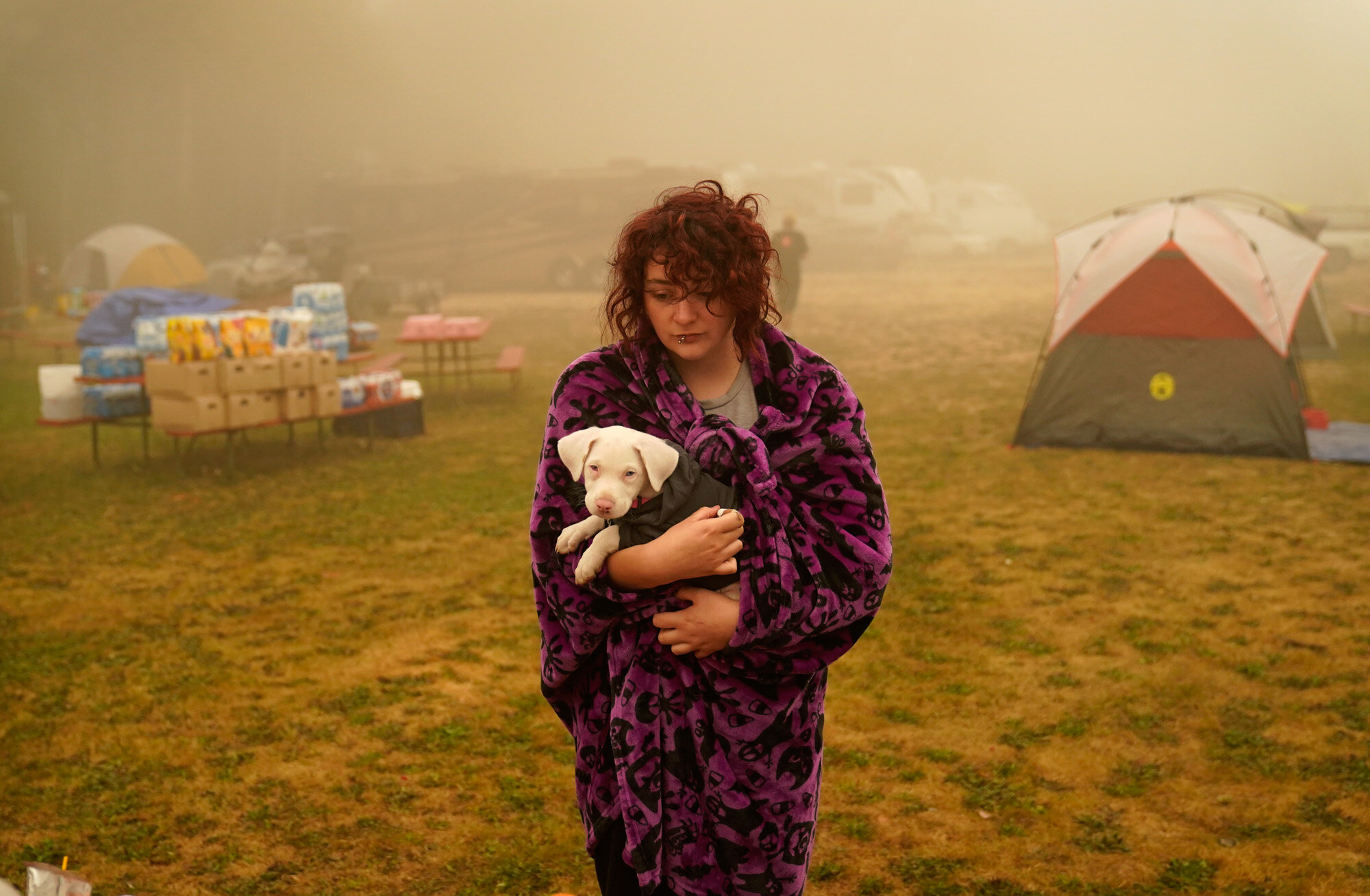 Shayanne Summers holds her dog Toph while wrapped in a blanket on Sept. 13, 2020, after staying several days in a tent at an evacuation center at the Milwaukie-Portland Elks Lodge in Oak Grove, Ore. Summers evacuated from near Molalla, Ore., which was threatened by the Riverside Fire. (AP Photo/John Locher)