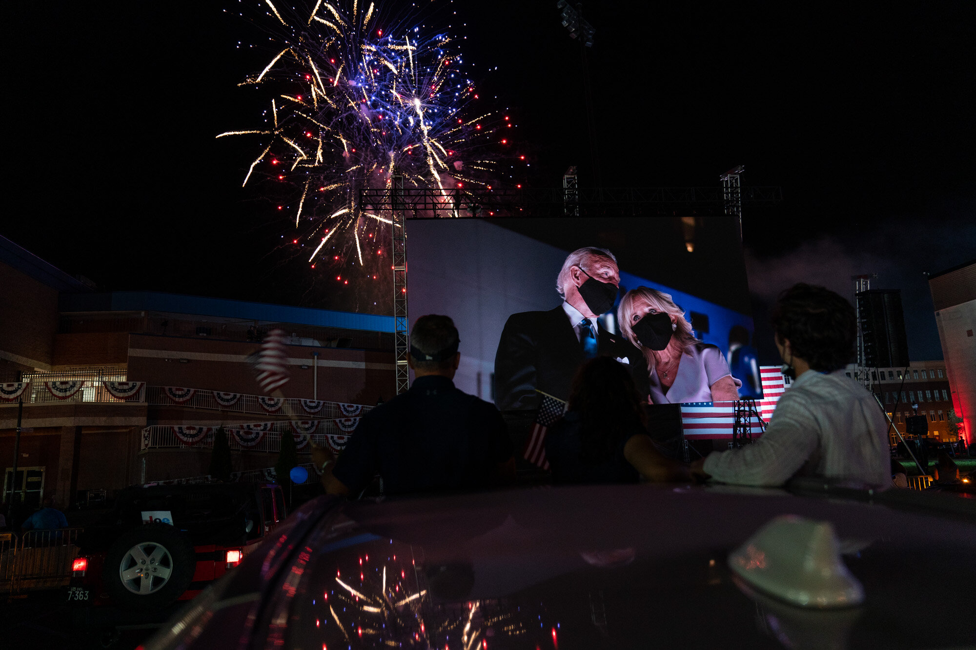 Supporters cheer from their cars as Democratic presidential candidate former Vice President Joe Biden and his wife Jill Biden appear on a huge monitor and fireworks light up the night sky on the fourth day of the Democratic National Convention in Wilmington, Del., on Aug. 20, 2020. (AP Photo/Carolyn Kaster)