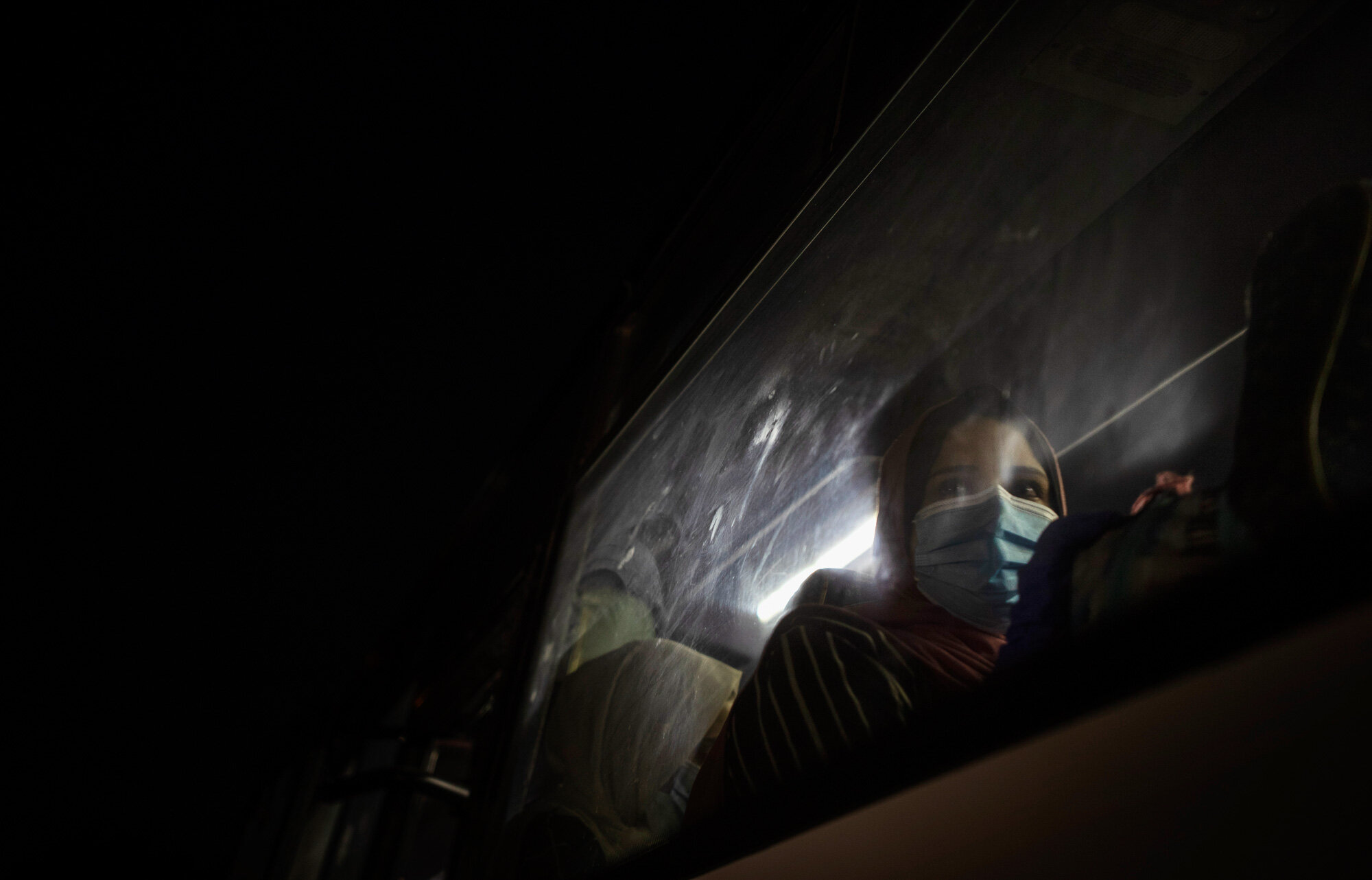 A Palestinian woman wearing a face mask to prevent the spread of the coronavirus waits in a bus in Gaza City to go to the Rafah border crossing into Egypt on Sept. 27, 2020. (AP Photo/Khalil Hamra)