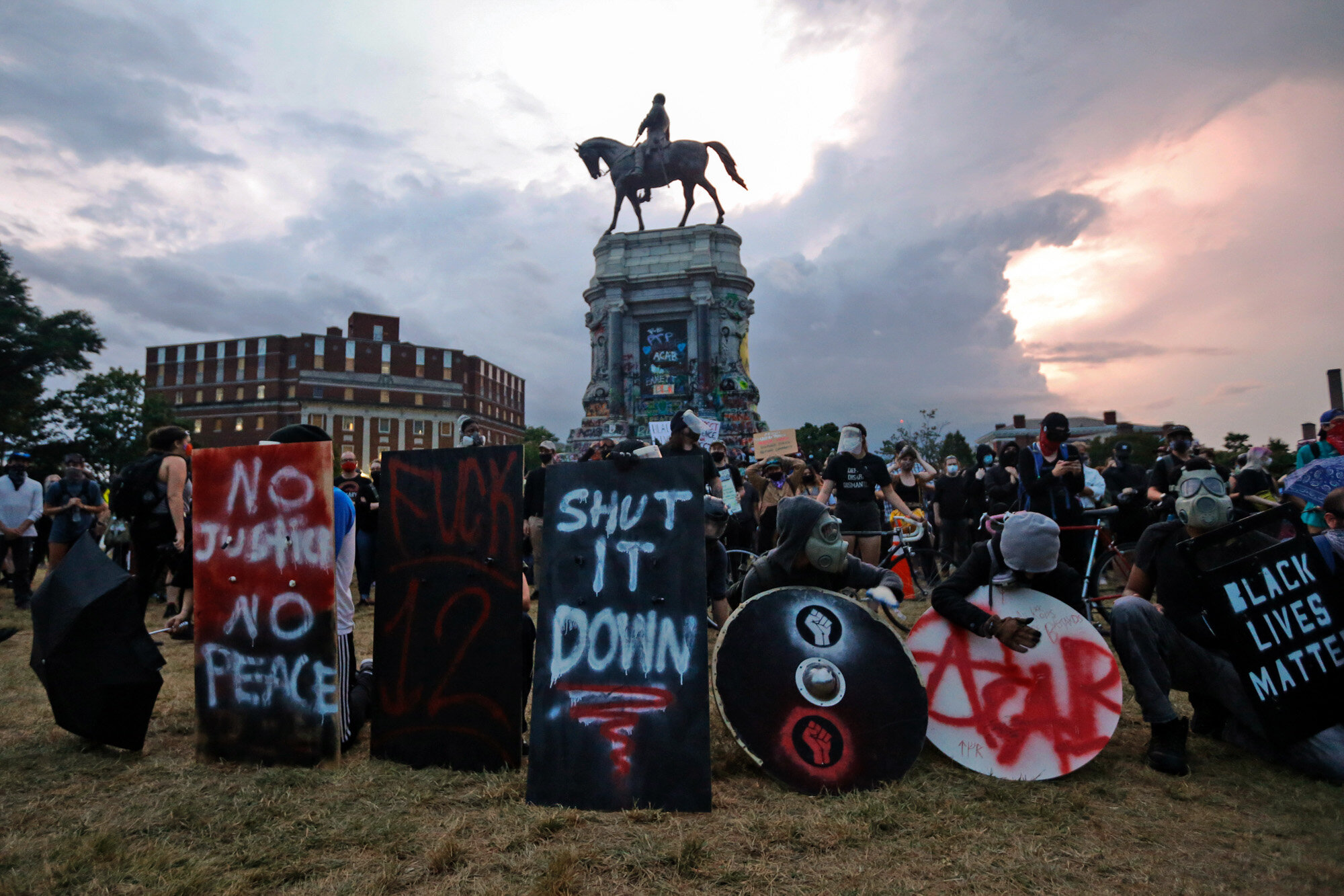 Protesters with shields and gas masks wait for police action as they surround the statue of Confederate Gen. Robert E. Lee on Monument Avenue in Richmond, Va., on June 23, 2020. The state ordered the area around the statue closed from sunset to sunrise, but the protesters had no plans to disperse. (AP Photo/Steve Helber)